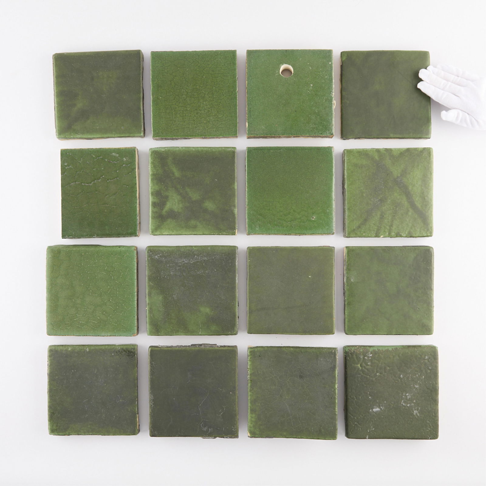 Grp 16 Green 6"x6" Grueby Tiles: Grueby Faience Company, Boston, Massachusetts. Group of 16 American Arts and Crafts enameled green ceramic pottery tiles, late 19th century. Several tiles stamped "Grueby Tile" and "Bos