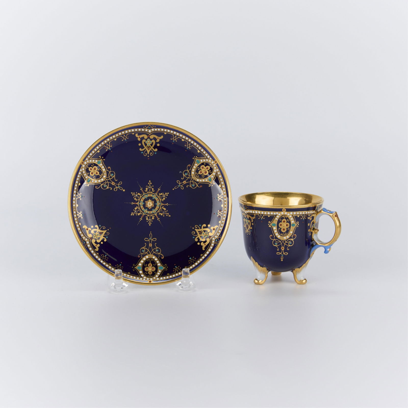 19th c. KPM Cobalt Blue Porcelain Cup & Saucer: KPM, Germany. Cobalt blue enameled porcelain teacup and saucer with gilt, 19th century. Stamped maker's mark along the underside of saucer.(Cup) height: 2 3/4 in x width: 3 1/2 in x depth: 2 3/4 in. (