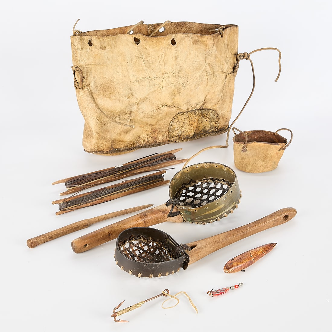 Group of Inuit Fishing Artifacts: Group of Inuit fishing artifacts, circa 1900, including:One walrus hide fishing bag from St. Lawrence Island in the Arctic.One seal skin bucket.Two ice scoops made of wood, bone, rawhide and baleen.Tw