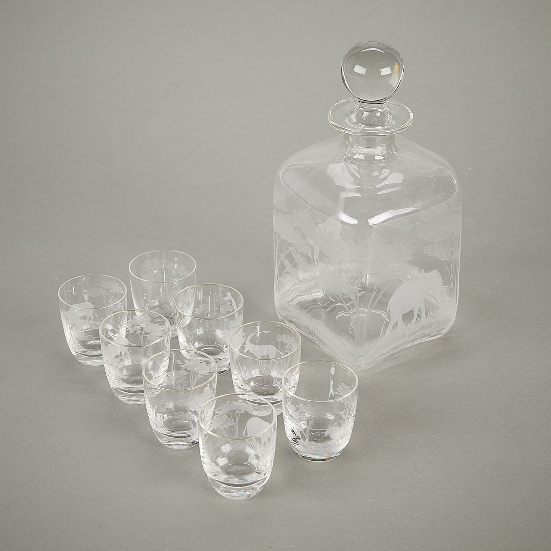9 Queen Lace African Wildlife Glassware: Queen Lace, Germany. Set of nine glassware, including one decanter and eight shot glasses, each etched with scenes of the Serengeti. Featuring depictions of African wildlife, including elephants, rhin