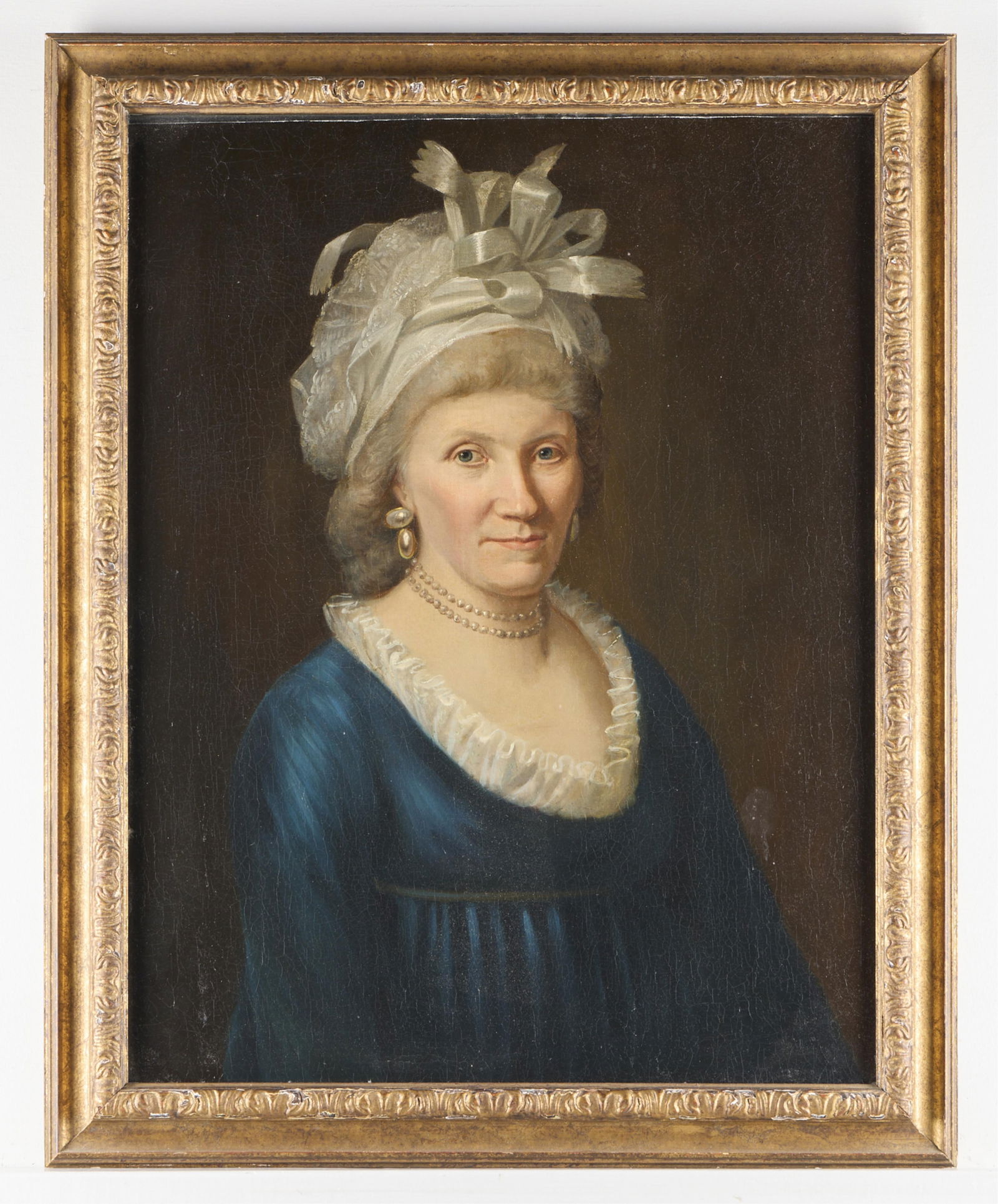 English School Portrait of a Lady in Blue Dress: Oil on canvas English school portrait painting depicting a lady in a lovely blue dress trimmed with white lace. She wears a fanciful white bonnet with white ribbons and is adorned with pearl jewelry.U