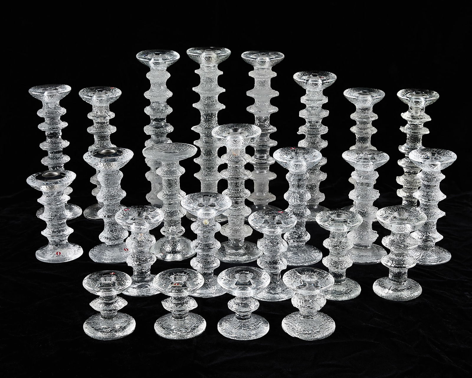 24 Timo Sarpaneva for Iittala Glass Candlesticks: Timo Sarpaneva (Finnish, 1926-2006) for Iittala, Finland. Group of 24 glass candlesticks of varying heights in avant-garde melting ice-inspired pattern "Festivo." Majority of the pieces with Iittala s