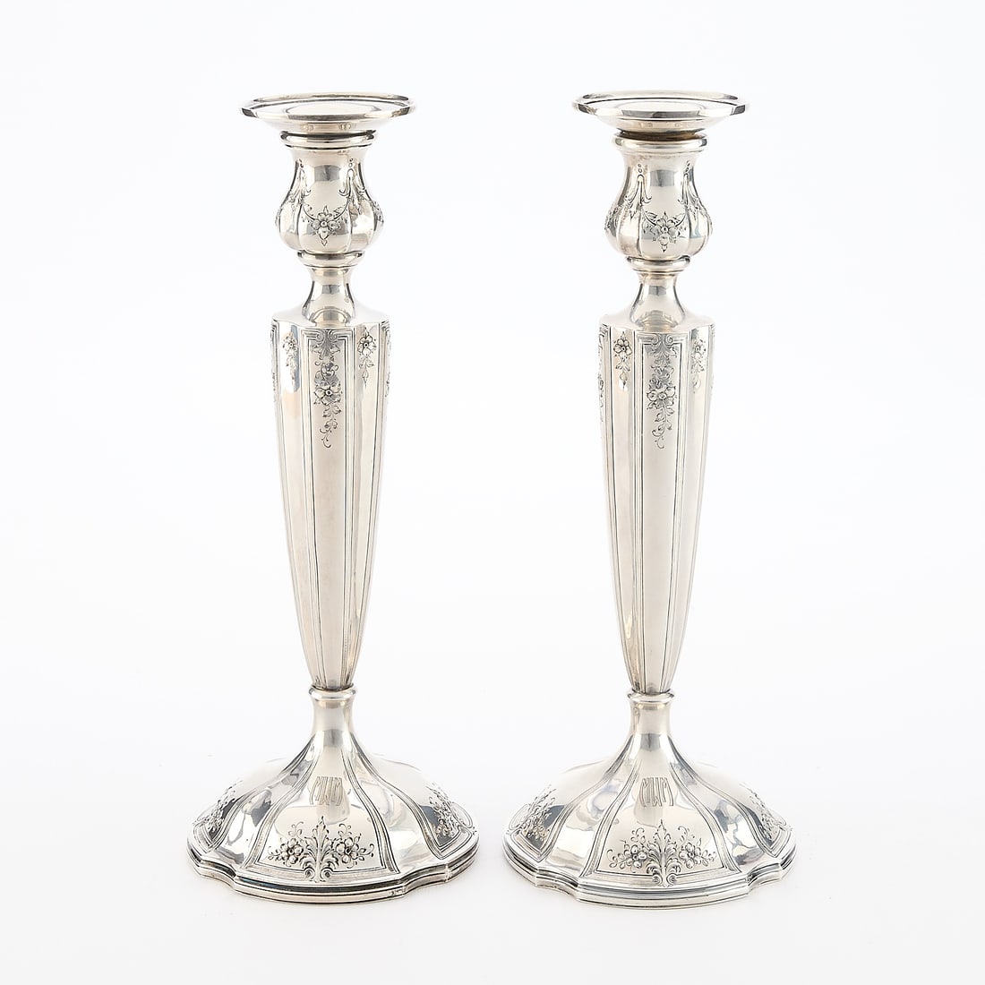 Pr American Weighted Sterling Candlesticks 1965.1g: Redlich & Co., New York. Pair of American weighted sterling silver candlesticks with floral motifs along the base and throughout the body, 1924. Engraved "MWM" along each base; marked "Sterling," "wei