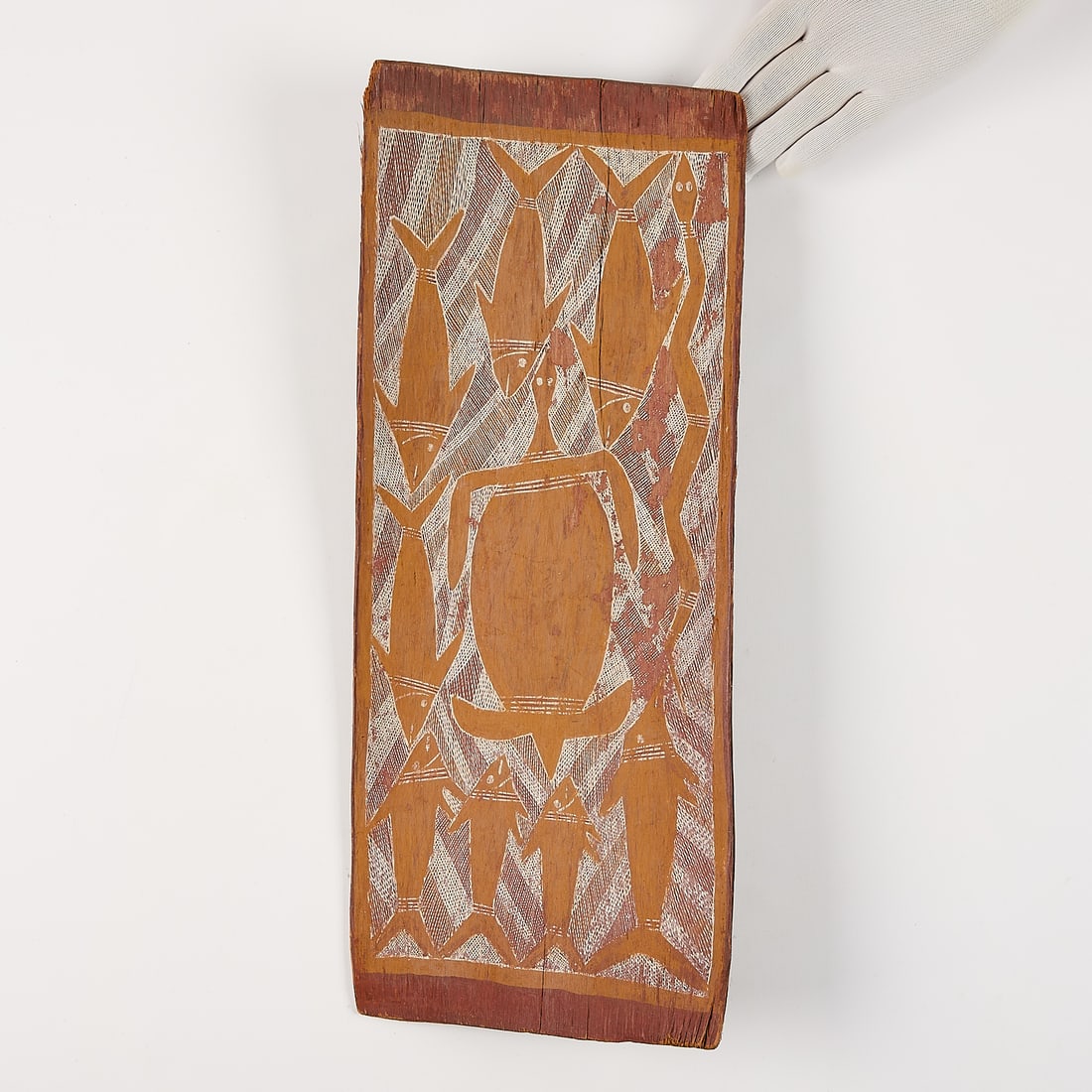 Australian Aboriginal Tjurunga Board w/ Fish: Australian Aboriginal carved wooden tjurunga (churinga) board depicting painted fish and a turtle amid cross-hatched geometric designs. Height: 21 in x width: 8 1/2 in x depth: 3 in.