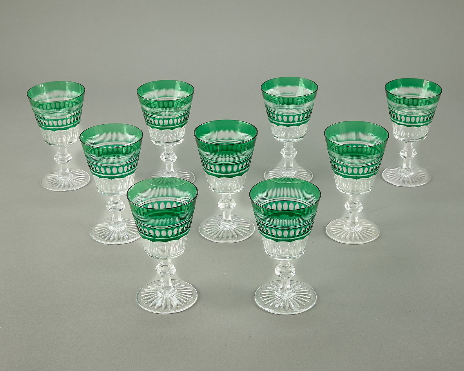 9 Emerald Green Cut Glass Crystal Wine Glasses: Group of nine cut glass crystal wine or aperitif glasses in emerald green. Each depicting geometric motifs. (Each) height: 6 1/4 in x diameter: 3 3/4 in.
