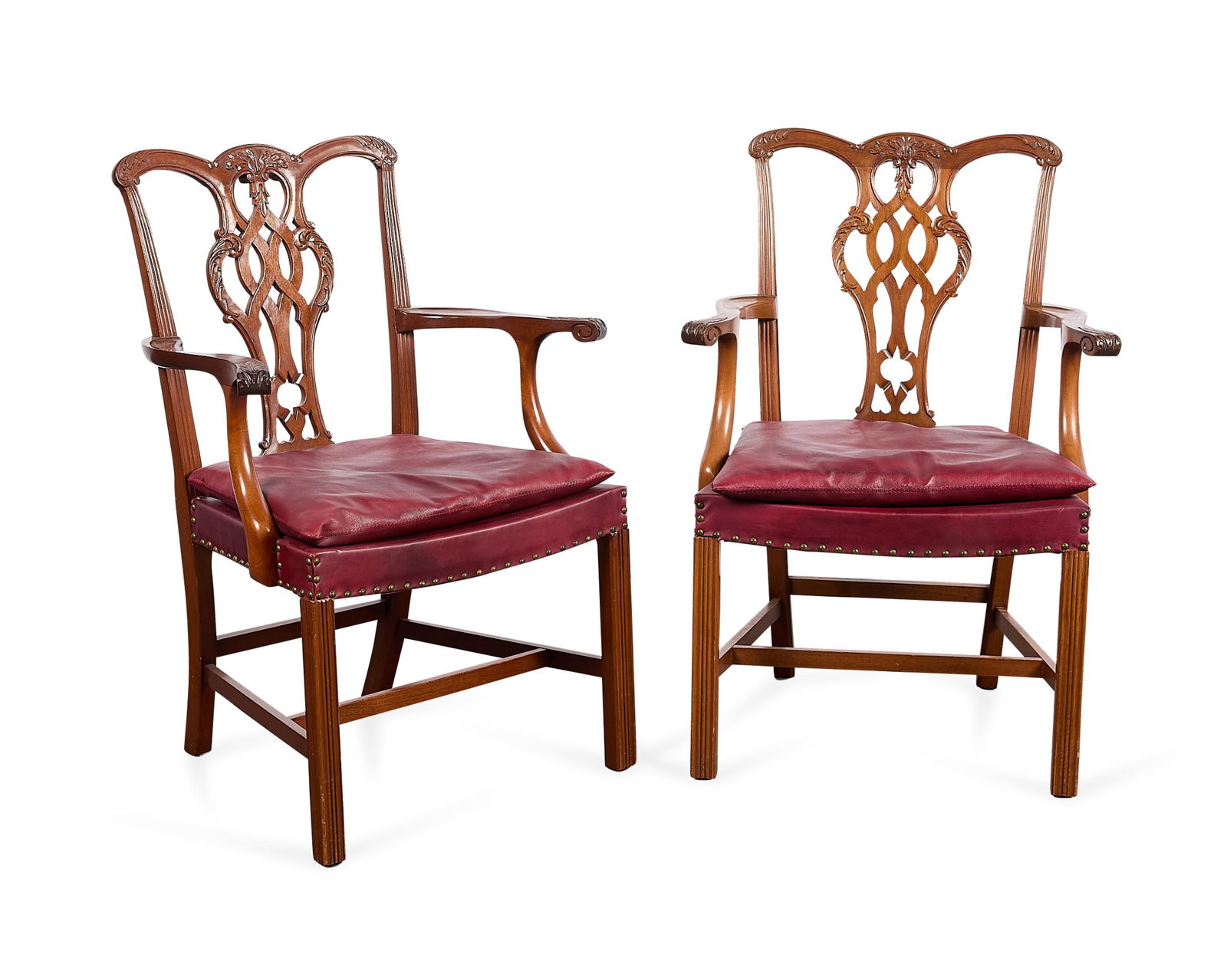 Pr Chippendale Style Living Room Armchairs: Pair of English Chippendale-style carved wood living room or "gossip" arm chairs, 20th century. With red leather seats and brass nailhead trim. The splats elegantly carved to depict scrolling foliate
