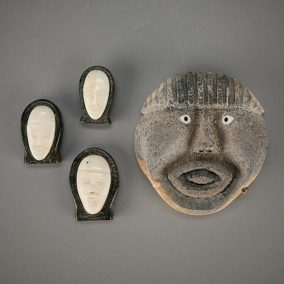 4 Inuit & Alaskan Carved Masks: Group of four Inuit and indigenous Alaska carved masks. Including:Patrick Nayokpuk (Alaskan (Inupiaq - Shishmaref), 20th/21st c). One carved fossilized organic material shaman's mask.Three Inuit (Qiki