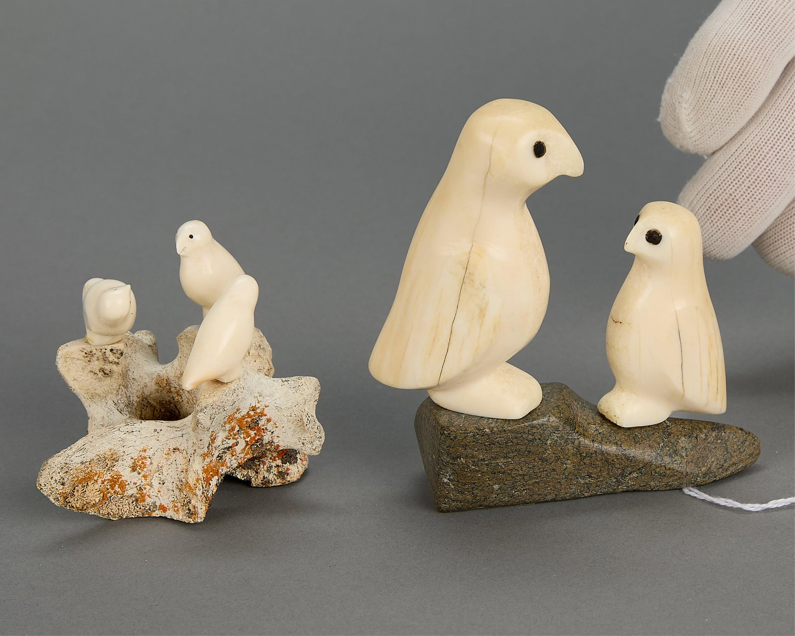 2 Inuit Bird Carvings: Group of two Inuit bird carvings including: Bernadette Iguptark Tongelik (Inuit (Naujaat - Repulse Bay), 1931-1980). Carved organic material owl and it's young on a stone base, signed in syllabics.