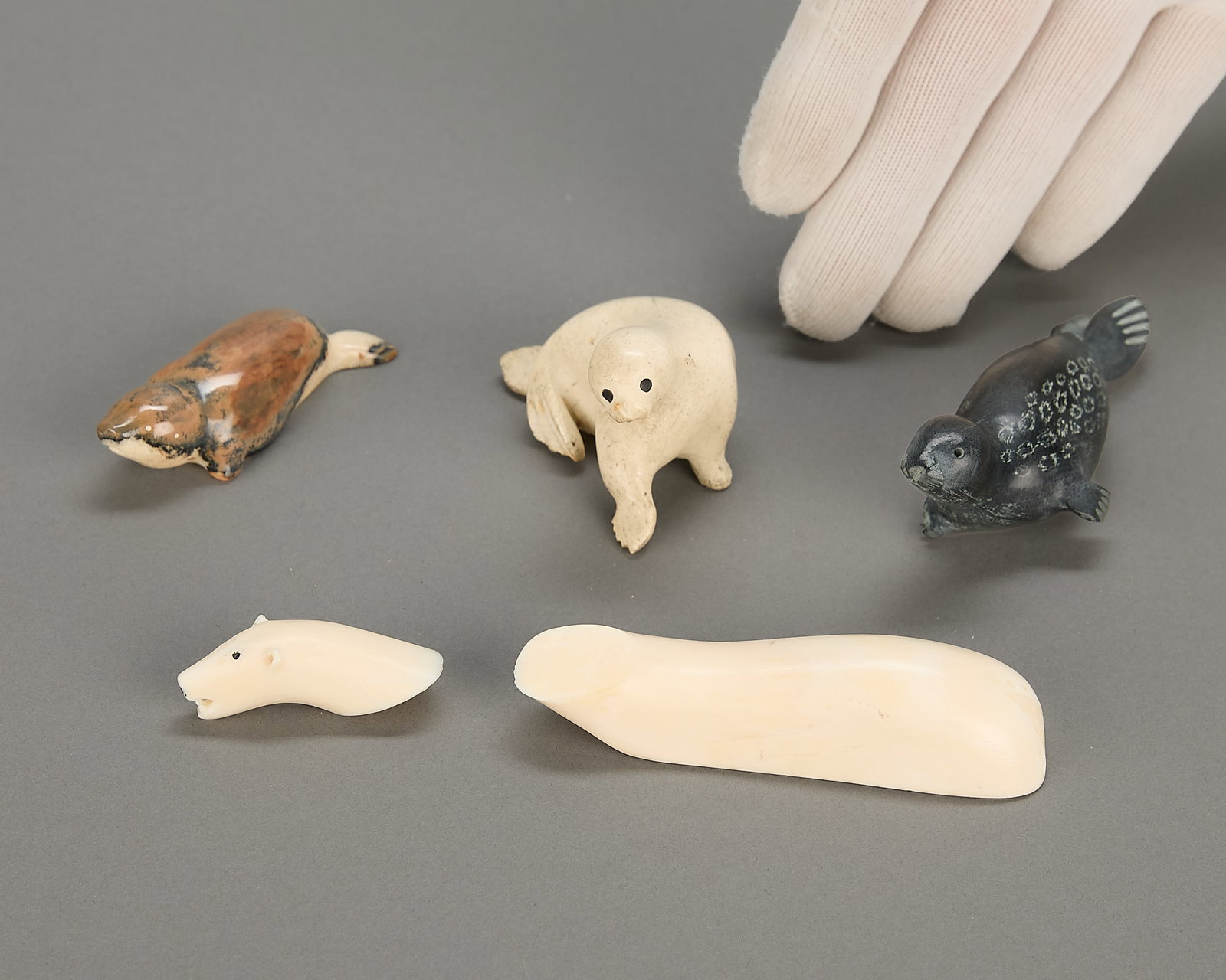 4 Inuit Seals & Polar Bear Carvings: Group of four Inuit carvings, including:One small seal carved from fossilized organic material, Chukchi, 1960s.One small seal carved from organic material, signed indistinctly for Felicite Kuwianartok