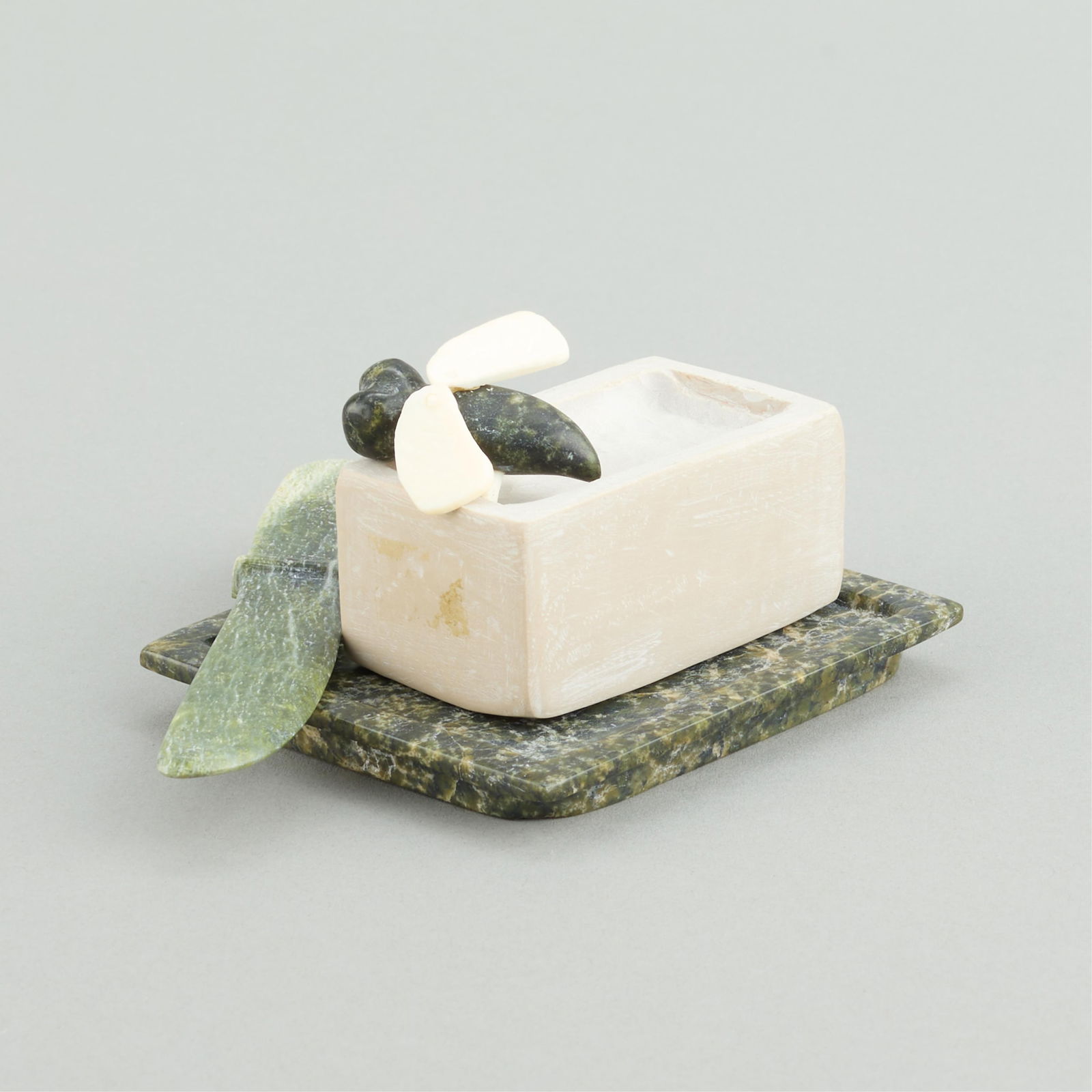 Jamesie Pudloo Pitseolak Buttery Fly Stone Carving: Jamesie Pudloo Pitseolak (Inuit (Kinngait - Cape Dorset), b. 1968). Carved stone and organic material sculpture in the form of a fly, accompanied by a stick of butter, knife, and butter dish. Resting