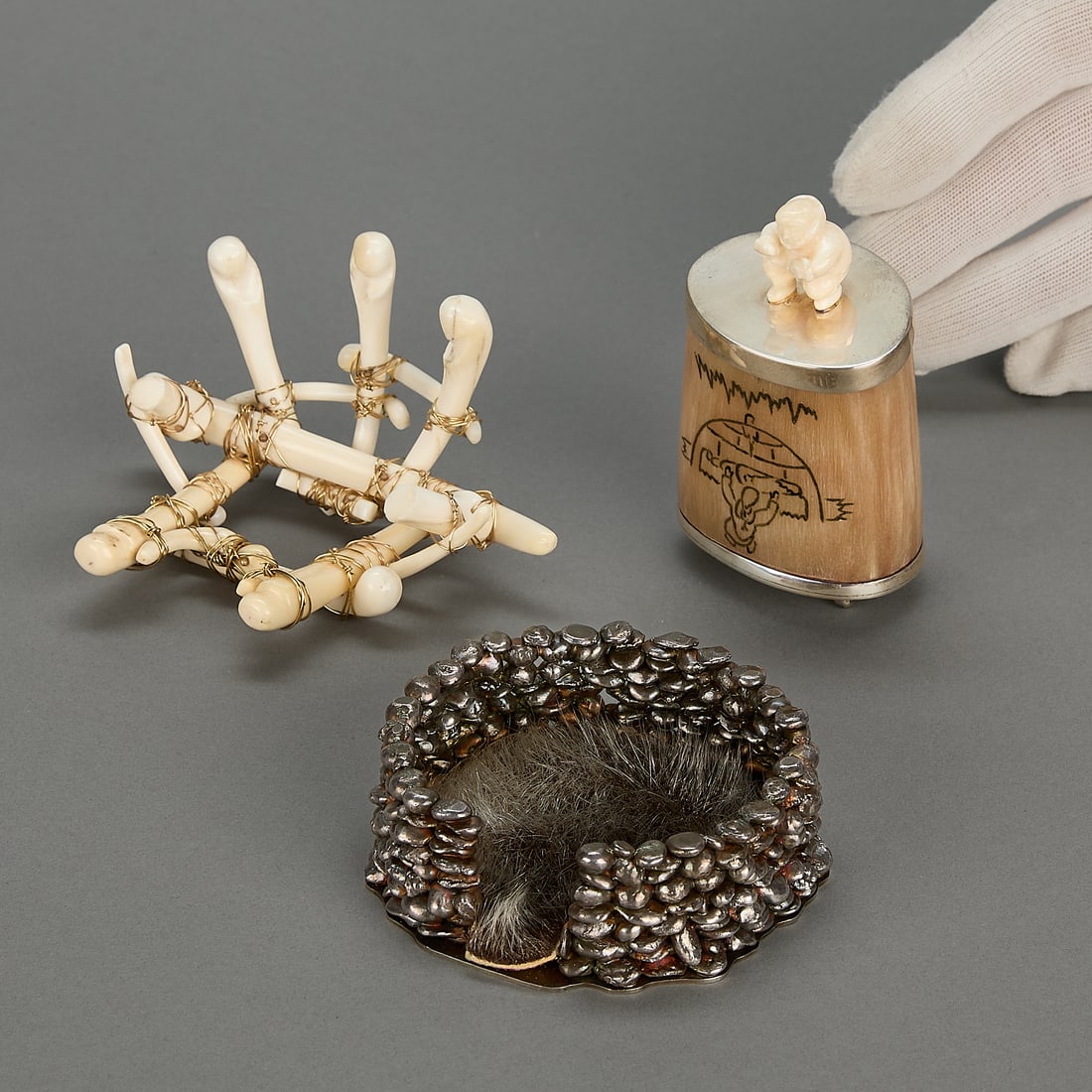 3 Inuit Sculptures w/ Metal: 3 Inuit sculptures mounted with metal including: One carved organic material sculpture, held together with gold tone wire. Unsigned. One semicircle of pebbled metal, on a flat base, with a small