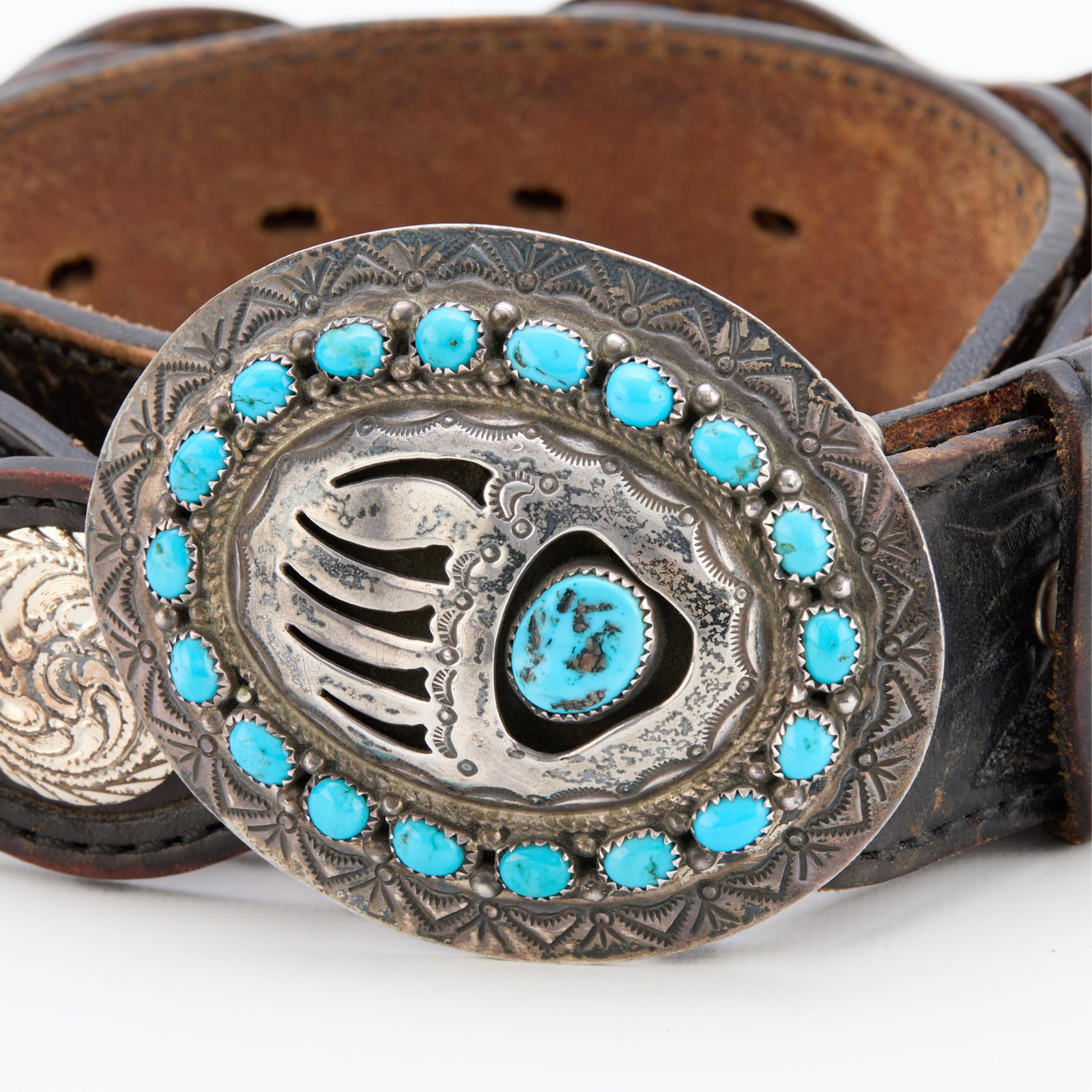 Wilbur Musket Navajo Sterling Buckle & Belt: Wilbur Musket (Navajo, b. 20th century). Silver belt buckle of oval form, with a central bear claw set with amorphous turquoise stone surrounded by a halo of smaller turquoise stones and stamp work. M