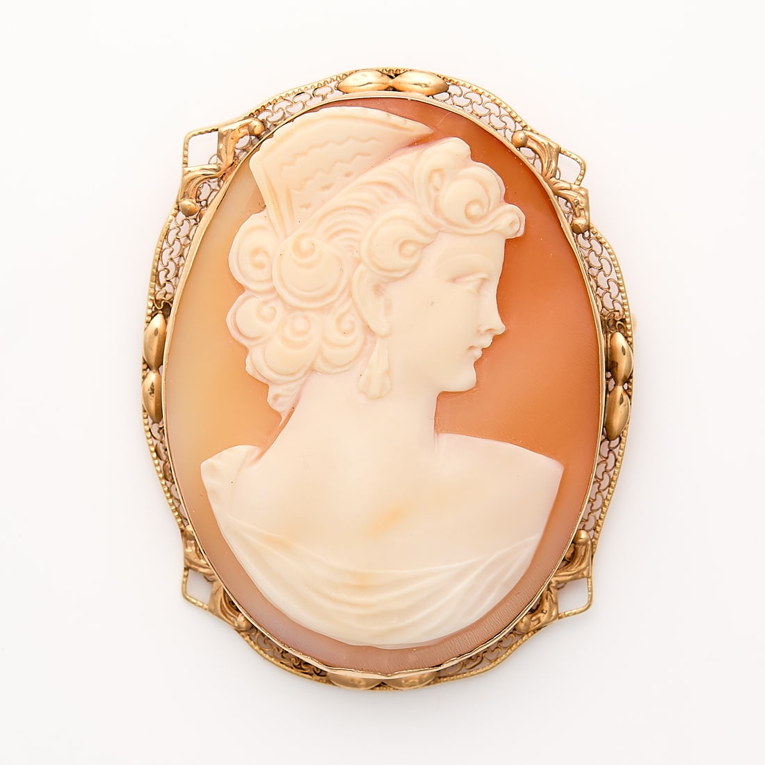 14k Yellow Gold & Carved Cameo: Carved shell cameo of a woman wearing a mantilla comb and large earrings, perhaps depicting traditional Andalusian dress. In a 14k yellow gold frame with filigree details. On a brooch clasp with hidde
