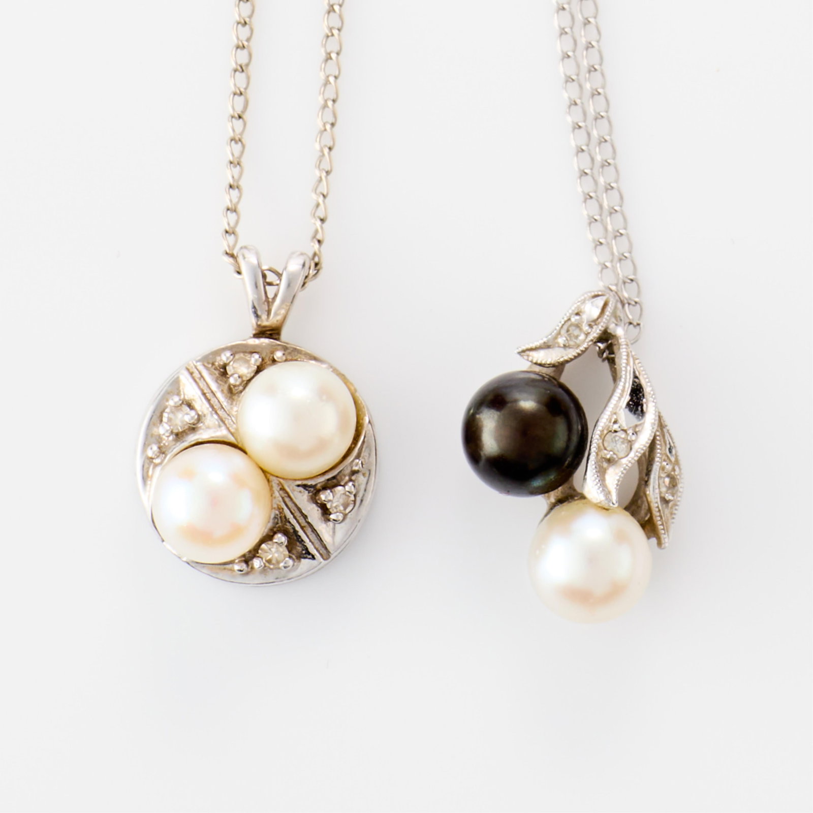 2 Pearl Pendants: Two pearl pendants, including:One on a gold filled chain, set with white and black pearl and three small single cut diamonds, the pendant unmarked, scratch tested 14k.One on a 14k white gold chain wit