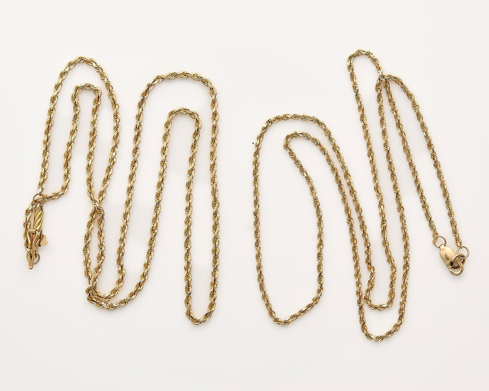 2 14k Yellow Gold Chains: Two 14k yellow gold chains including one 14k yellow gold rope chain marked 14k near the lobster clasp. One 14k yellow gold rope chain on a barrel clasp, marked 14k near the clasp. (Each) Length: 18