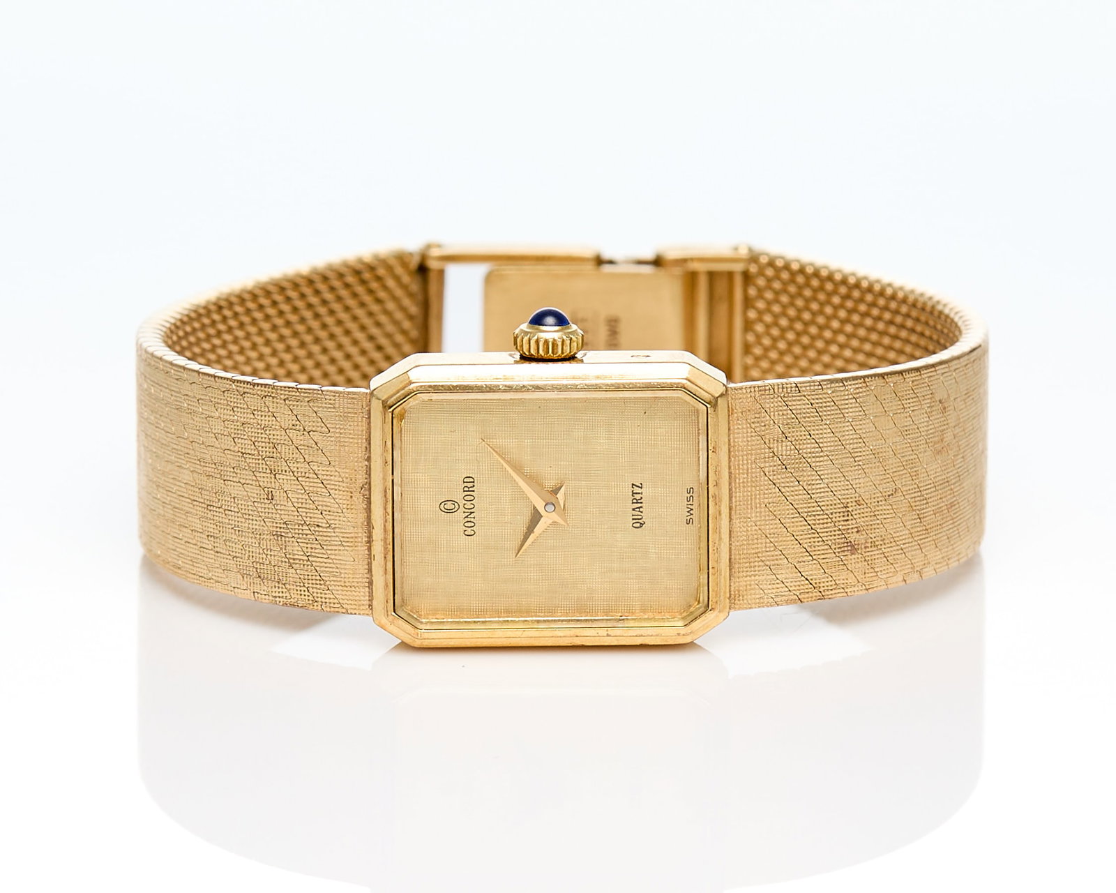 14k Yellow Gold Concord Watch: 14k yellow gold Concord quartz watch with rectangular gold case, on a textured gold bracelet, with a gold face & hand with no indices. On a fold over clasp with three settings. Marked variously for