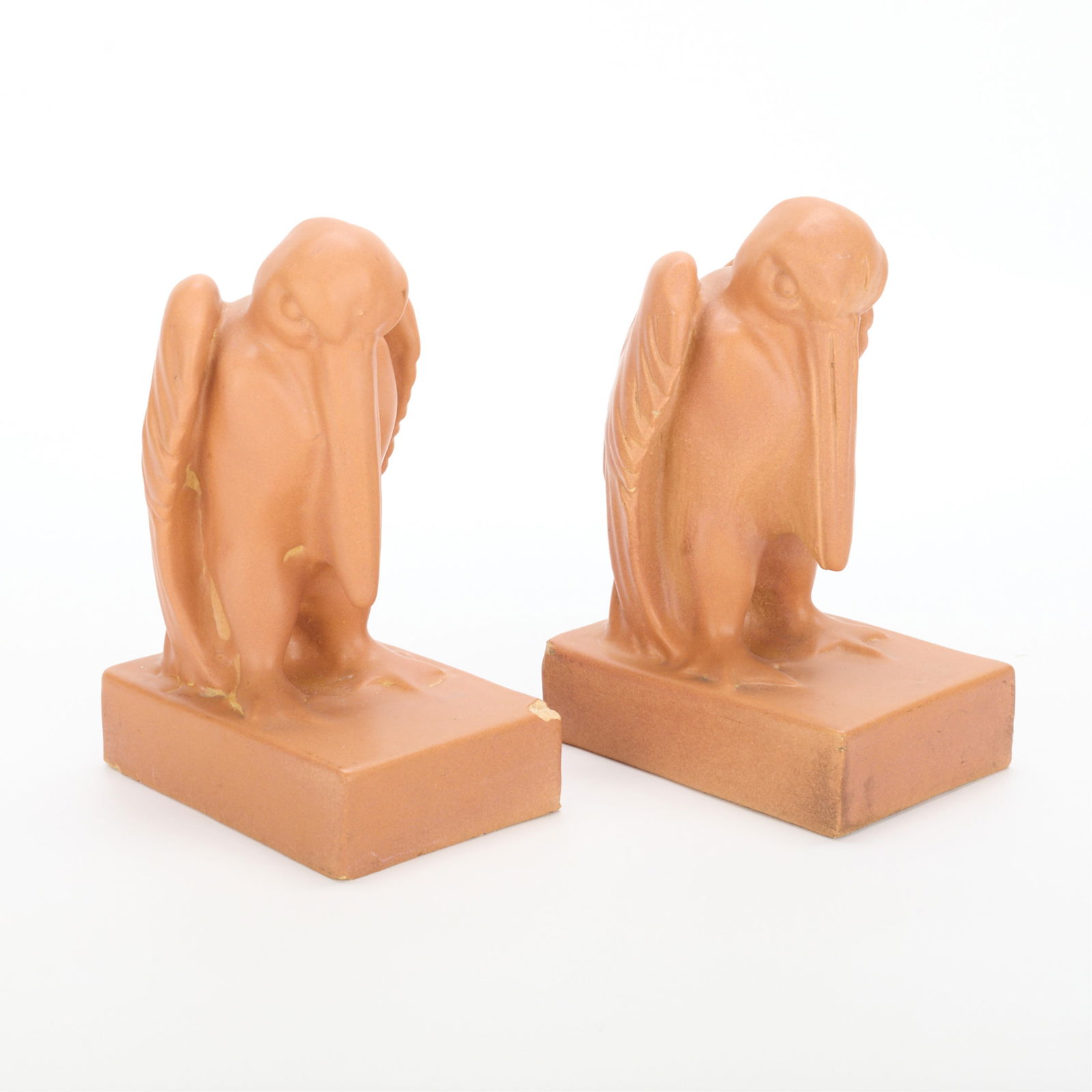 Pr American Terra Cotta Pottery Pelican Bookends: American Terra Cotta & Ceramic Company, Illinois, United States. Pair of art pottery ceramic bookends depicting perched pelicans, ca. 1905. Executed in a coral or orange glaze. Impressed stamp mark al
