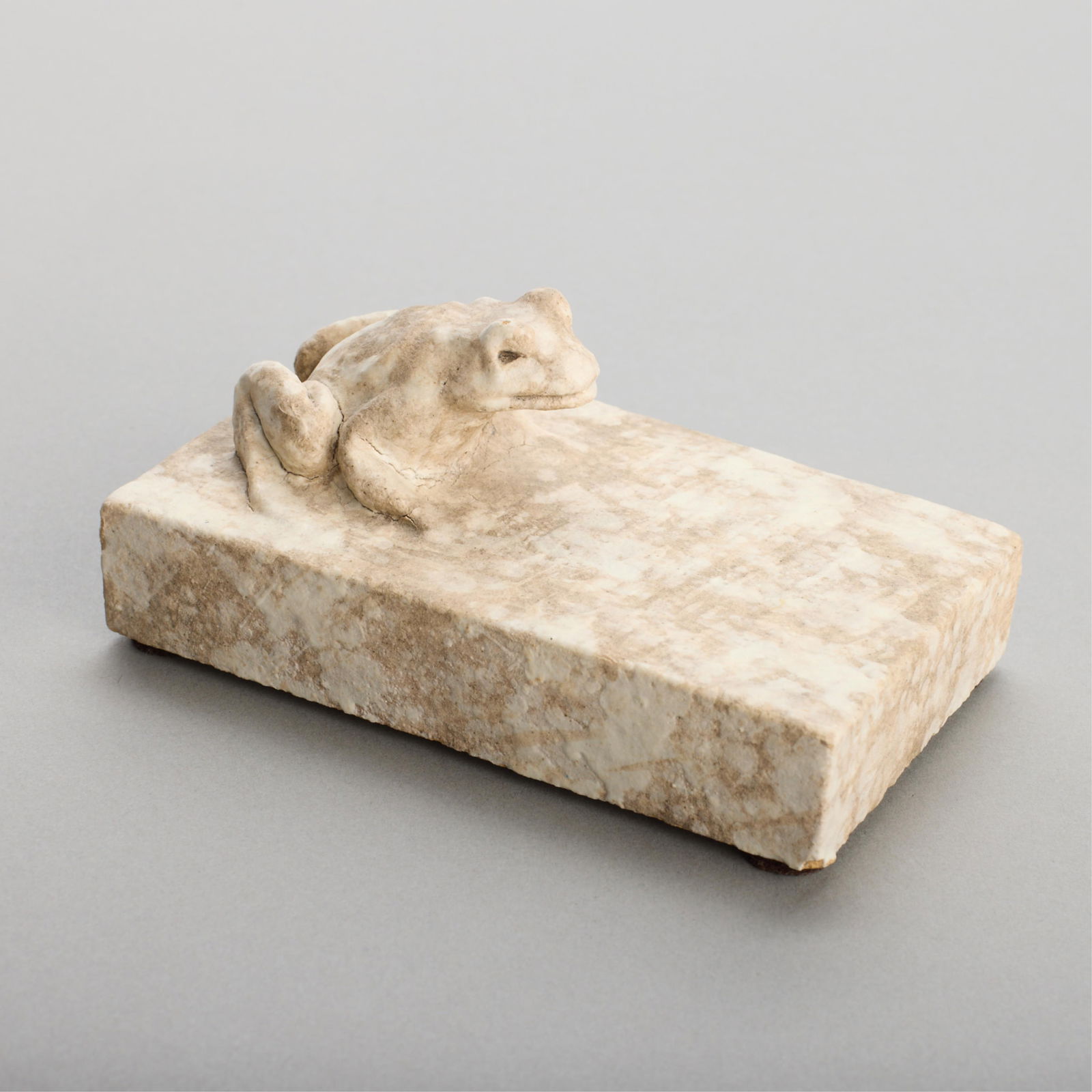 American Terra Cotta Art Pottery Frog Paperweight: American Terra Cotta & Ceramic Company, Illinois, United States. Art pottery paperweight in the form of a crouching frog positioned atop a block. Executed in a speckled white and grey glaze. Impressed