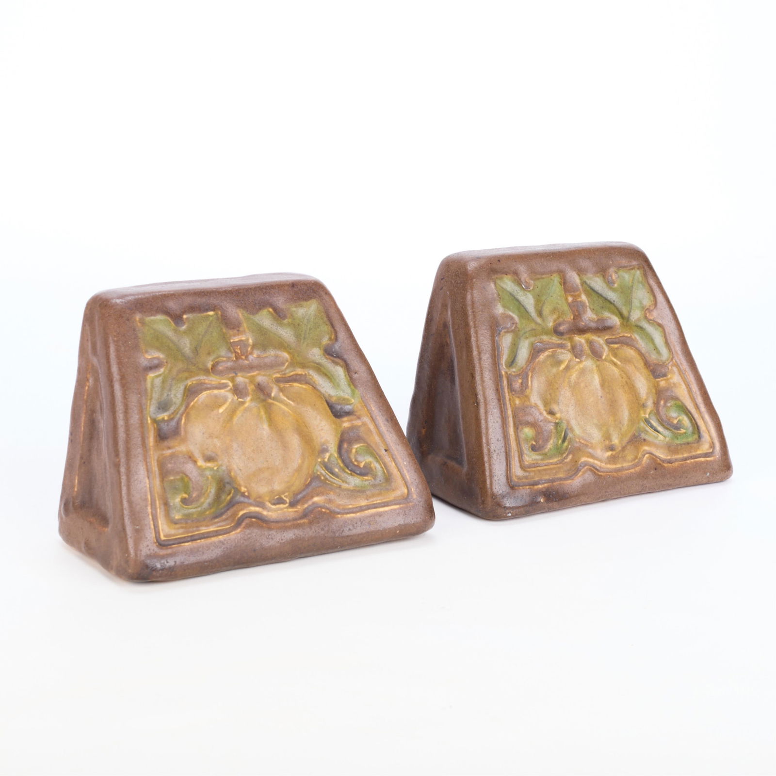 Pr Handicraft Guild Arts & Crafts Ceramic Bookends: Handicraft Guild of Minneapolis, Minnesota. Pair of Arts & Crafts glazed earthenware bookends, ca. 1905. Depicting ripe fruit, possibly peaches or tomatoes, in relief. Each with partial paper labels