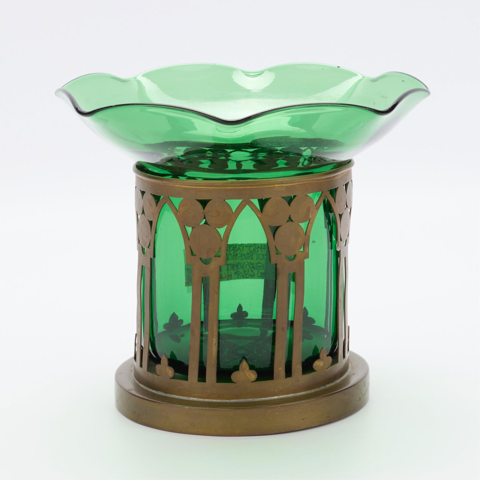 Pairpoint Co. Arts & Crafts Brass & Glass Vessel: Pairpoint Manufacturing Co., United States. Arts & Crafts vase vessel composed of a brass cut-out base with emerald green glass insert, early 20th century. The insert with undulating and ruffled rim;