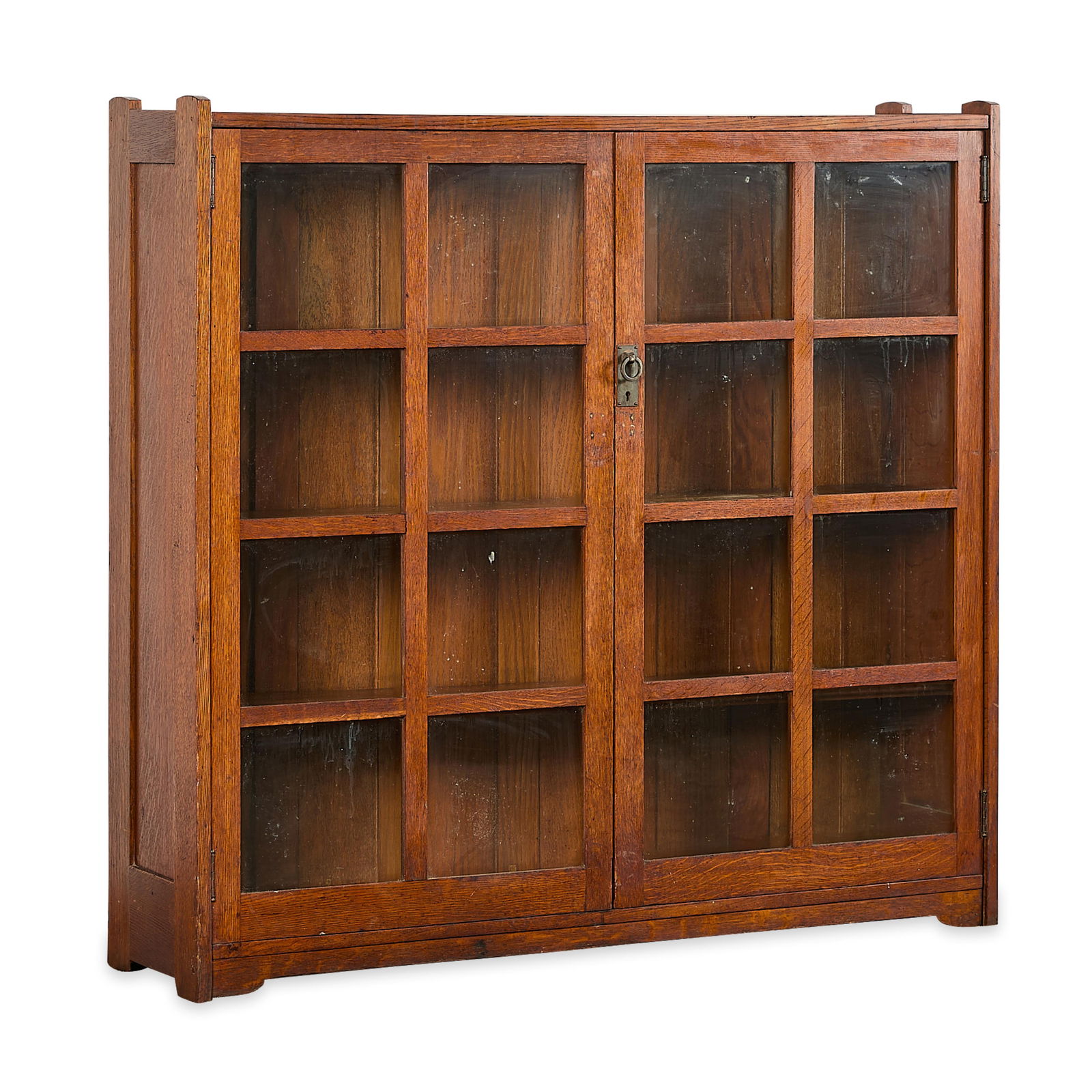 Style of Stickley Arts & Crafts Oak Cabinet: Style of Stickley Arts & Crafts Mission oak two-door china or curio display bookshelf cabinet, early 20th century. Featuring two doors with copper pulls and glass panes, segmented into eight squares.