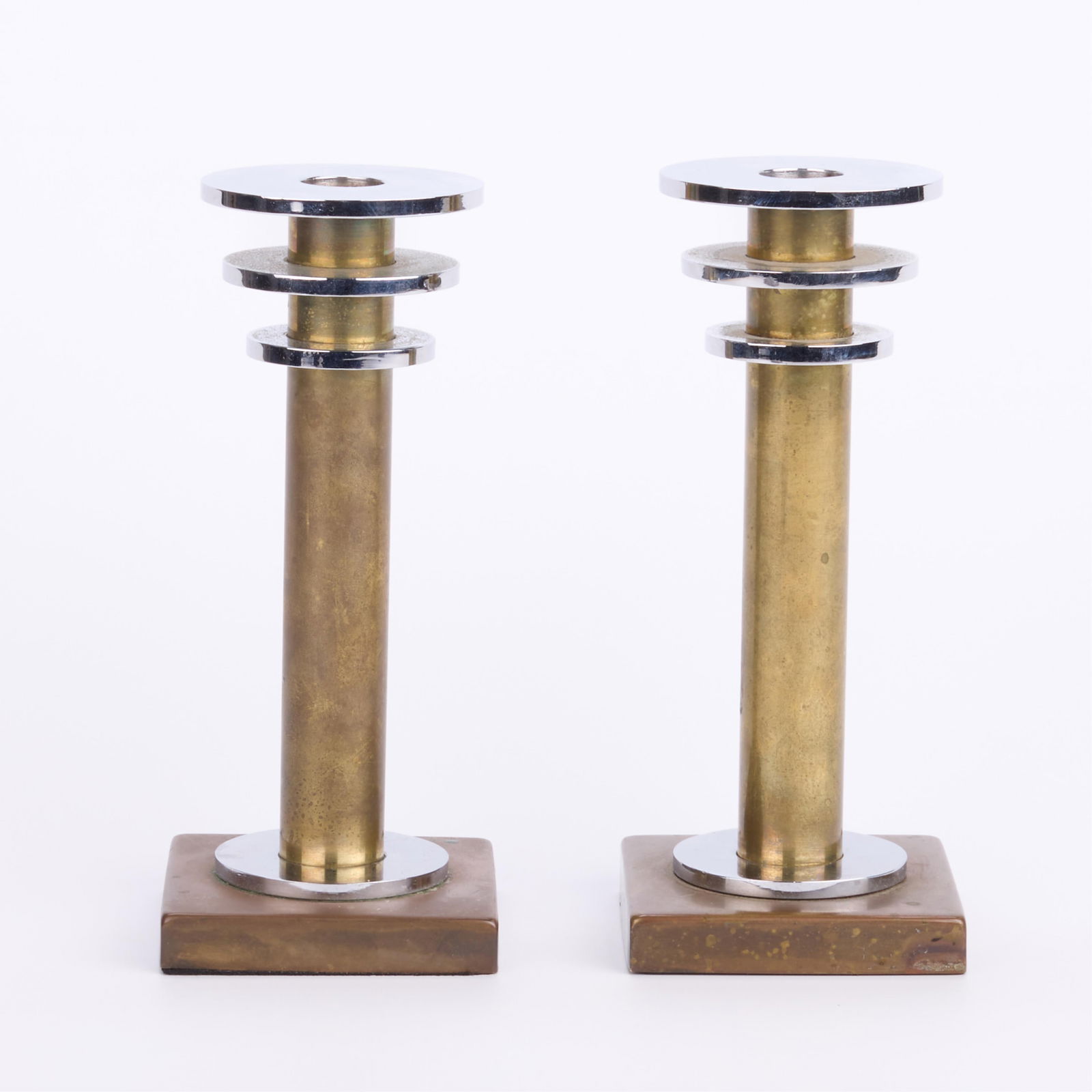 Pr Machine Age Brass & Chrome Candlesticks: Pair of Machine Age or mid-century modern brass candlesticks or candleholders. Each featuring three concentric chrome circles along the top.(Each) Height: 8 1/4 in x width: 3 1/2 in x depth: 3 1/2 in.
