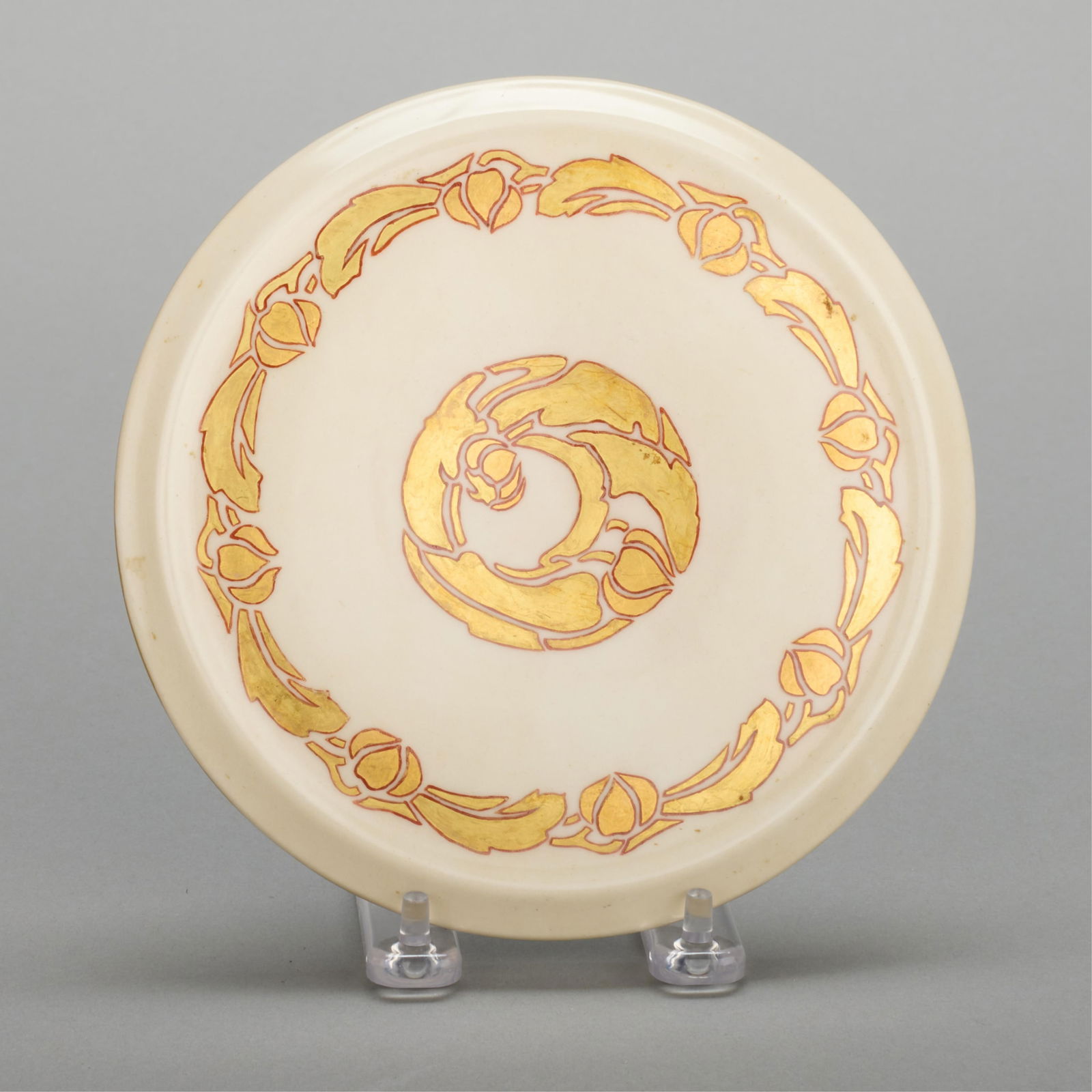 Hilma Berglund Art Nouveau Gilt Porcelain Trivet: Attributed to Hilma Berglund (American, 1886-1972). Art Nouveau porcelain trivet, depicting gilt foliate motifs. Stamped along the underside. Diameter: 7 in.