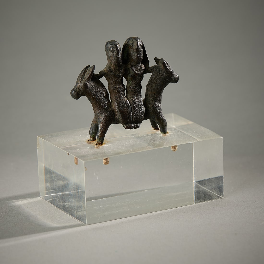 Luristan Bronze Horse with Couple Figurine: Ancient Luristan bronze depicting a male and female figure seated atop a double-sided horse, Iran, ca. 1000-600 BCE. (Not incl. stand) Height: 2 in x width: 2 1/4 in x depth: 1/2 in.