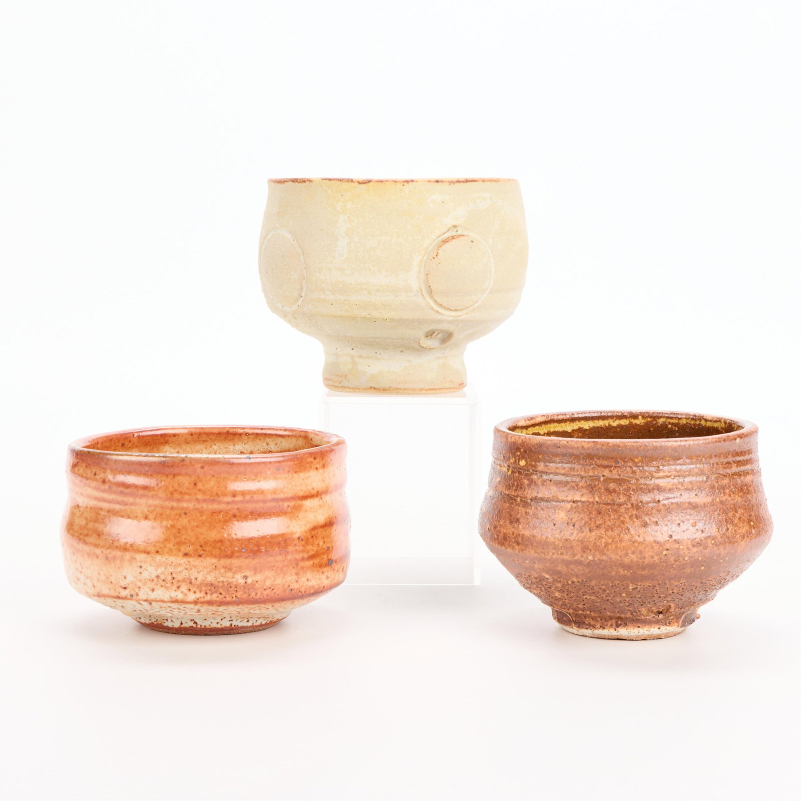 3 Warren MacKenzie Studio Pottery Bowls - Marked: Warren MacKenzie (American, 1924-2018). Group of three studio pottery ceramic footed chawan tea bowl vessels. Stoneware with varying glazes, including shino. Each marked along the footrim. Warren MacK