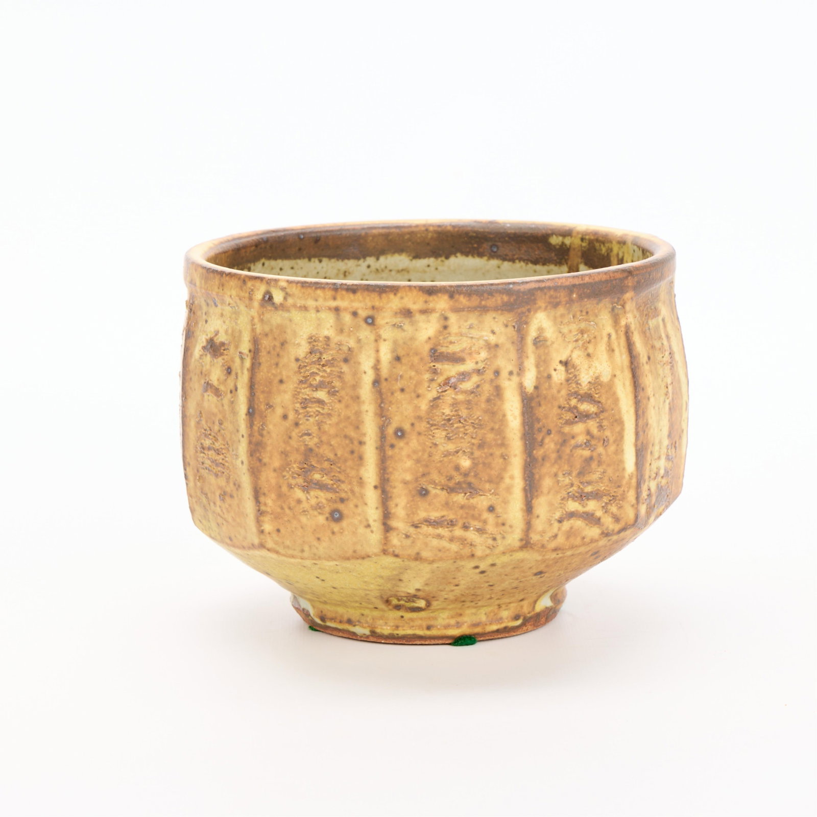 Warren MacKenzie Pottery Faceted Bowl - Marked: Warren MacKenzie (American, 1924-2018). Studio pottery ceramic faceted and footed bowl vessel. Stoneware with a matte yellow glaze. Stamped along footrim. Warren MacKenzie was a renowned Minnesota stu