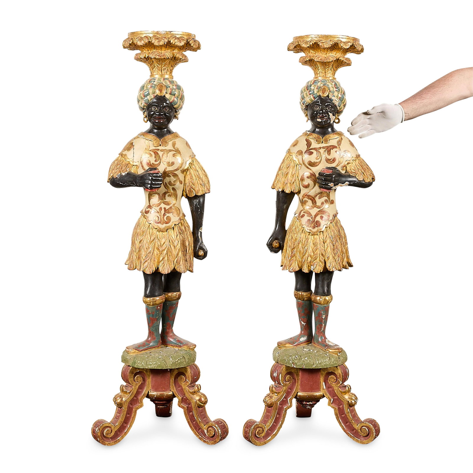 Pr Italian Painted Giltwood Blackamoor Torcheres: Pair of Italian polychrome and carved giltwood blackamoor torcheres, 19th century. The figures don striped head coverings and gilt adorned garments decorated with plumed detailing. Atop rounded bases 