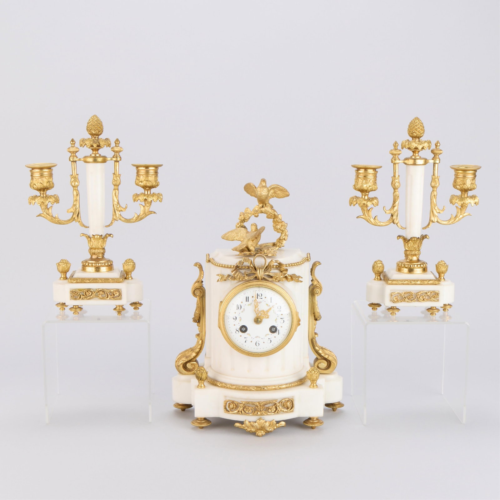 3 Pc Louis XVI Marble & Ormolu Garniture Set: French Louis XVI white marble and gilt bronze garniture set, 19th century. Including a mantle clock and a pair of two-light candelabra. Featuring elegant scrollwork and foliate motif mounts. The clock