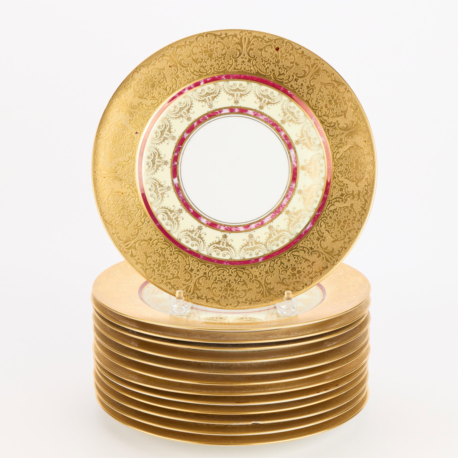 13 Furstenberg Germany Porcelain Dinner Plates: Furstenberg, Germany. Set of 13 porcelain dinner plates, 20th century. Each with Rococo-style motifs, red banding, and acid-etched gilt borders. Each stamped with a crowned blue "F" mark and "Germany"