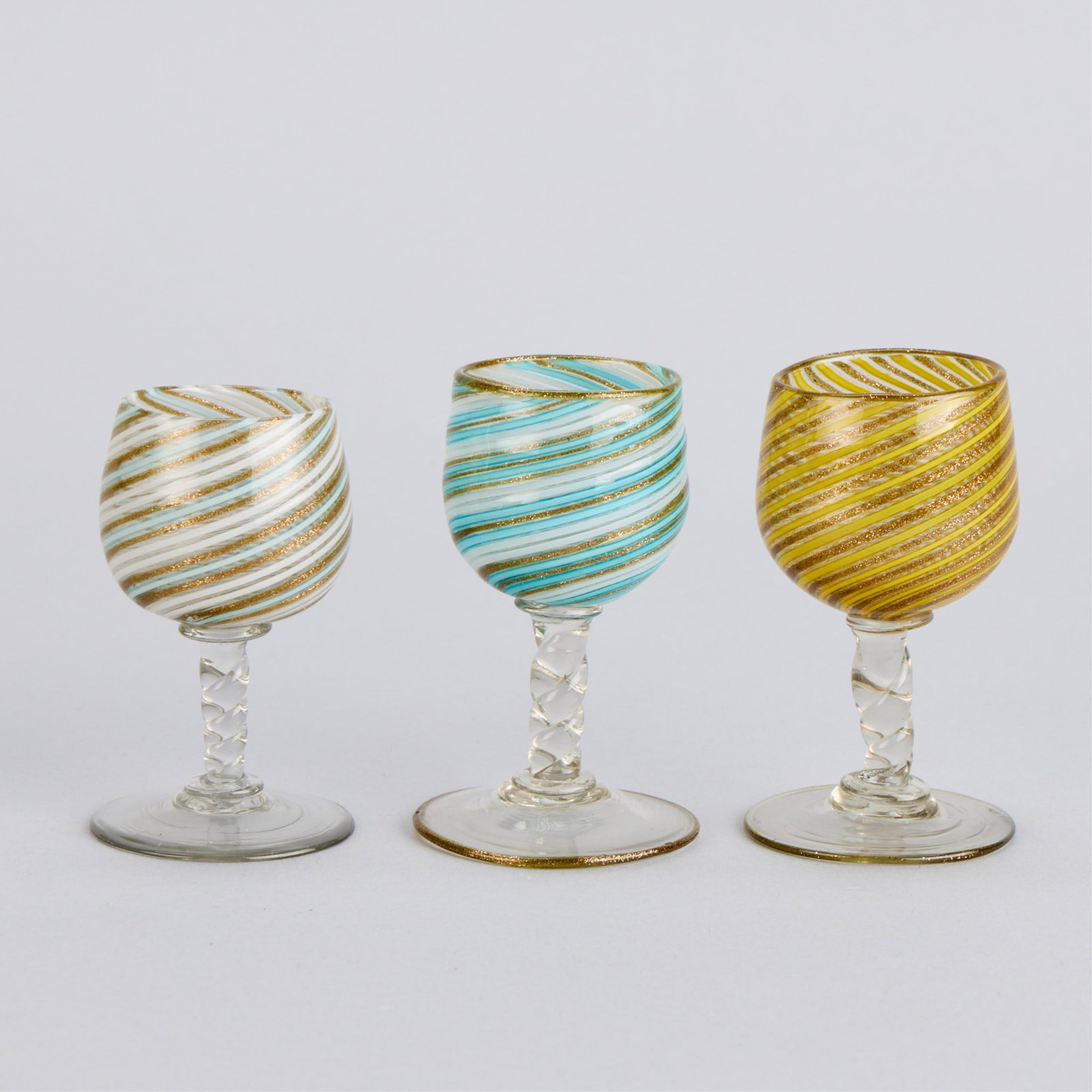 3 Style of Salviati Murano Mezza Filigrana Glasses: Style of Salviati & Company, Italy. Group of three Venetian Murano glass cordial cups or tazza drinking glasses, 20th century. Each with banded "mezza filigrana (half-filigree)" motif swirling along t