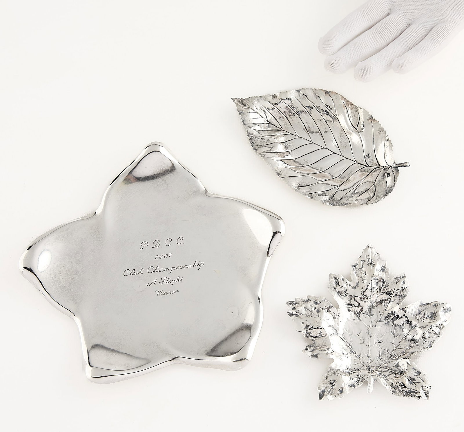 3 Sterling Trays Incl. Tiffany & Co. - 10.015 ozt: Group of three sterling silver trays. Including: Elsa Peretti (Italian, 1940-2021) for Tiffany & Co., United States. One tray in the form of a star. Engraved to read "PBCC 2007 Club Championship A
