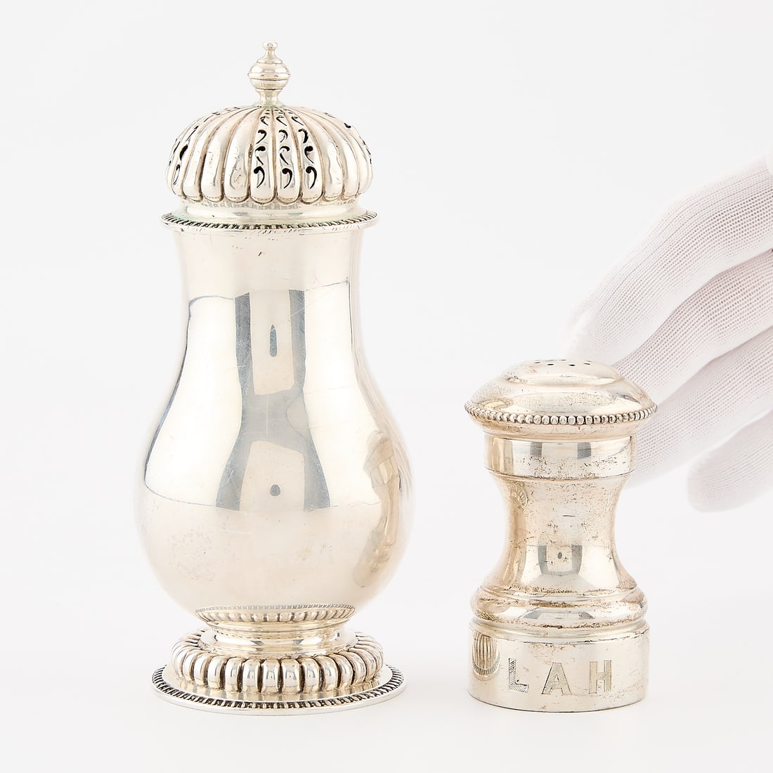 2 Sterling Silver Casters: Group of two sterling casters including: One sterling silver pepper caster with full wooden interior and turned wood screw mechanism, with initials LAH and marked France along the wood and Revere ster