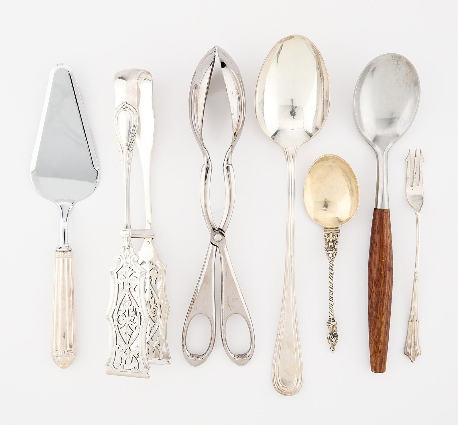 7 Misc. Silverplate & Steel Utensils 964.9 g: Group of seven silverplate and stainless steel utensils. Including: Six silver plate utensils, comprising one set of asparagus tongs, one cake server, one set of salad tongs, one fish serving spoon, o