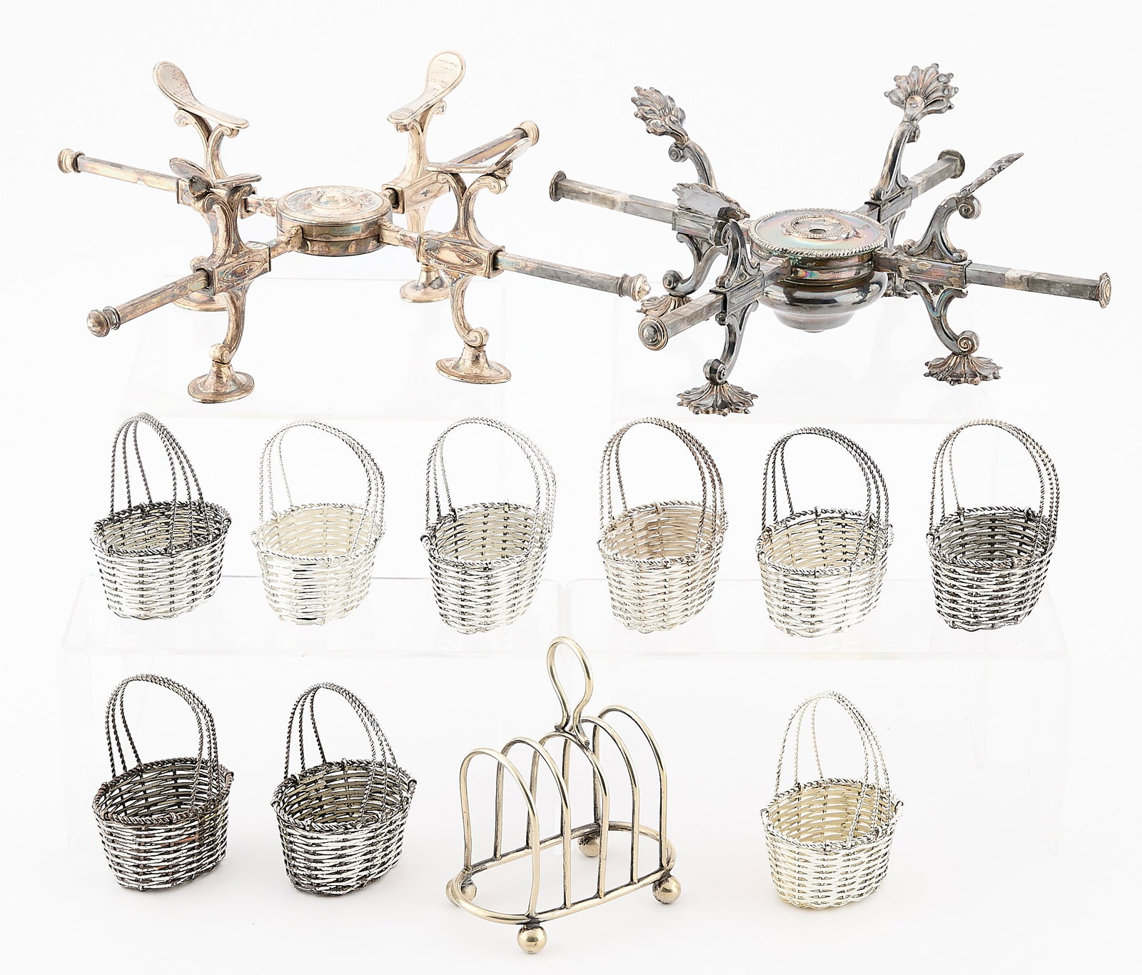 12 Pcs Misc. Silverplate - 2,130.4 g: Group of 12 miscellaneous silverplate table objects. Including: Two adjustable dish crosses or warming trivets. One four-slot toast rack. Marked "EPNS." Nine small woven silver plate baskets. Produced