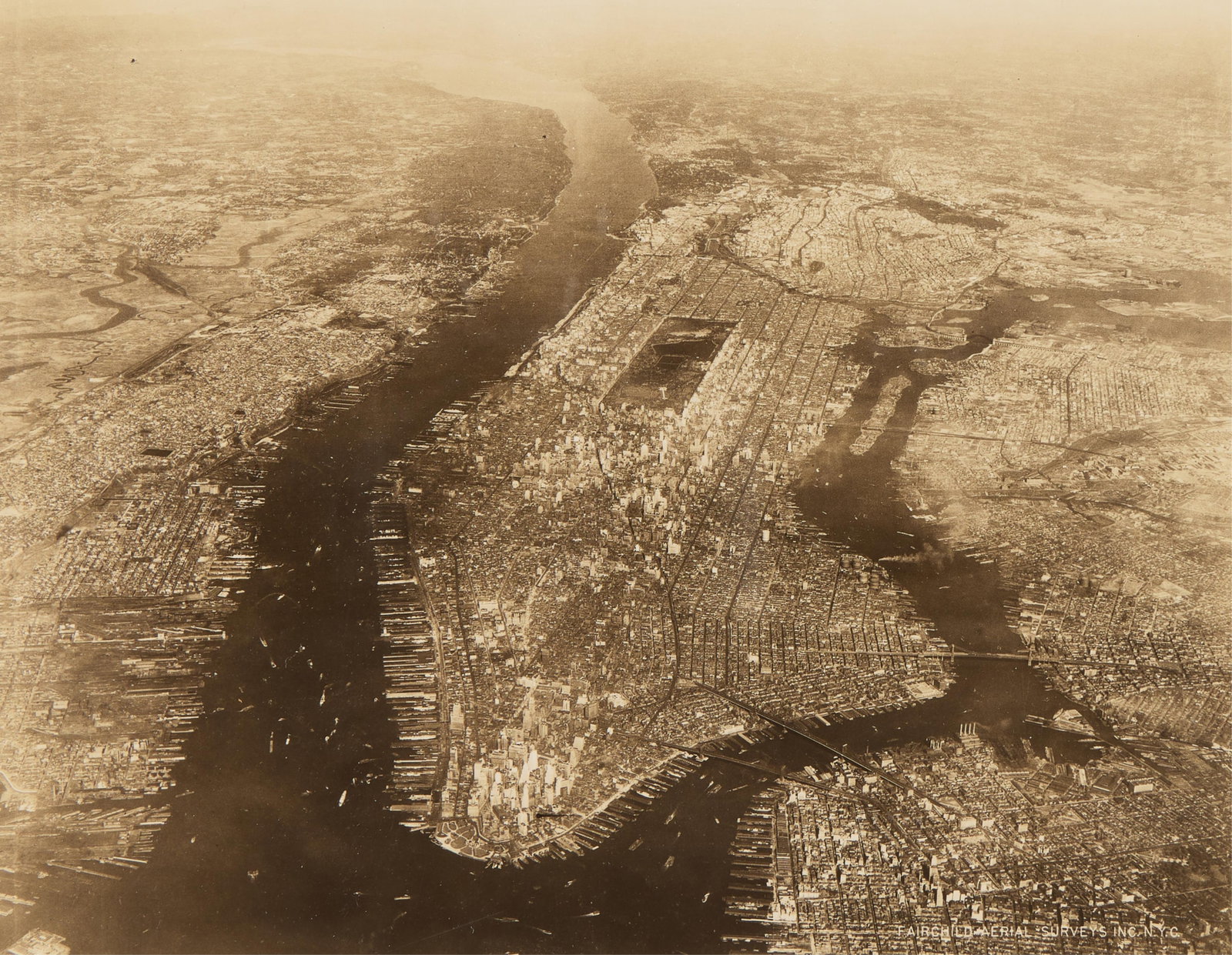Fairchild Aerial Surveys Manhattan NYC Photograph: Fairchild Aerial Surveys, Inc., United States. Sepia-toned photograph depicting an aerial view of Manhattan in New York City, ca. early 20th century. Ink stamped and pencil numbered 51054 along the ve