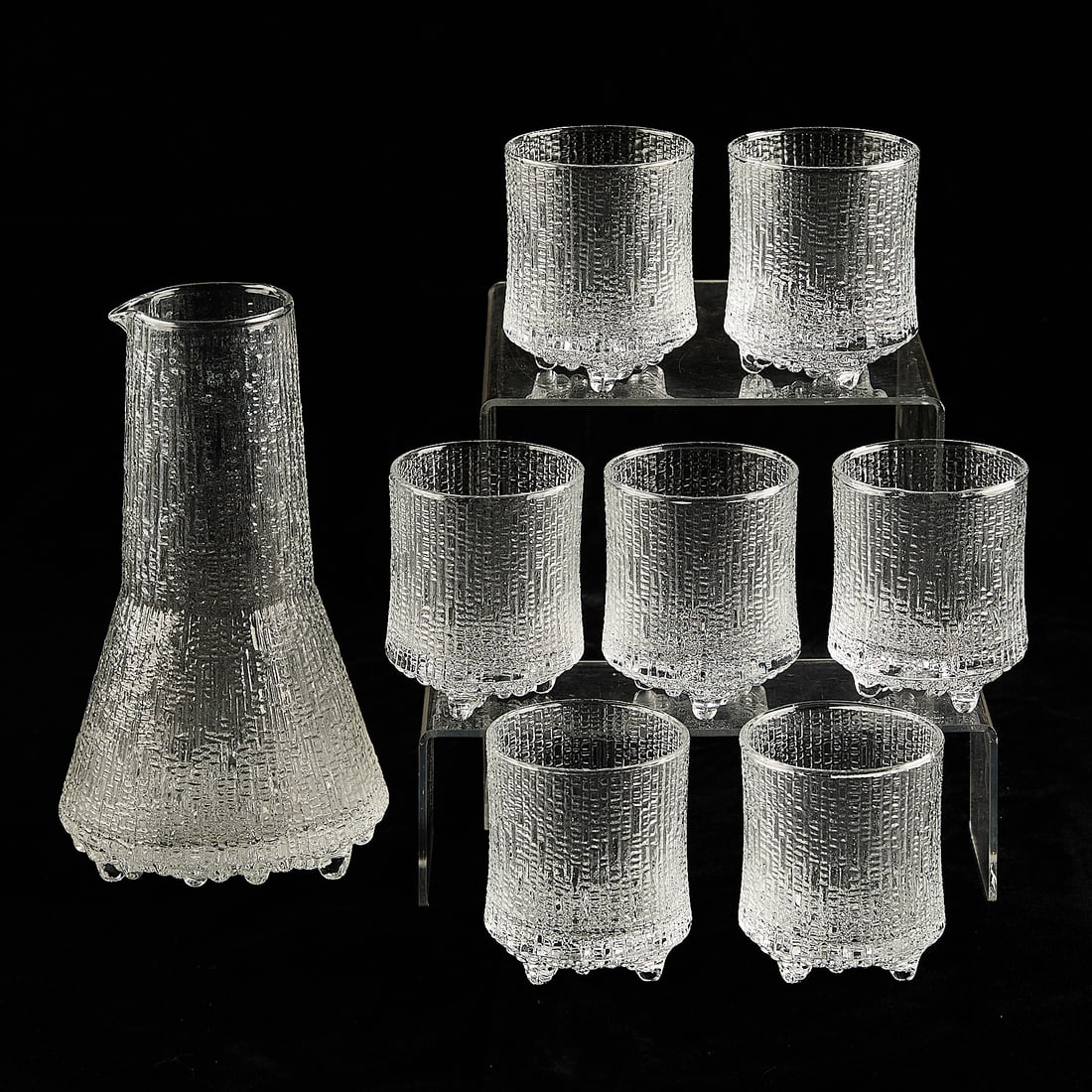 8 Iittala "Ultima Thule" Glass Tumblers & Pitcher: Tapio Wirkkala (Finnish, 1915-1985) for Iittala, Finland. Set of eight pieces of "Ultima Thule" patterned glassware, 20th century. Comprising seven tumblers and one pitcher. Each resting on three roun