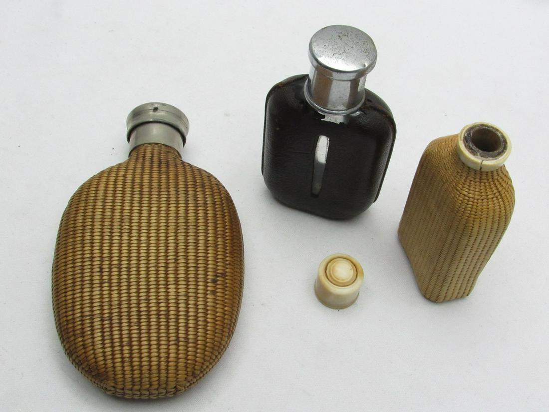 An Assortment Of 3 Flasks, Antique Carrying Bottles For Hard Liquor: An Assortment Of 3 Flasks, Antique Carrying Bottles For Hard Liquor, circa 1900, including two glass bottles covered with a braided wicker straw net (Wicker Flask): one with a screw-on metal banderole