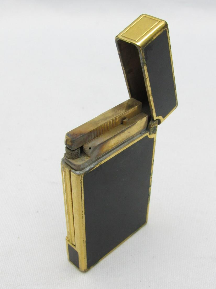 Metal Lighter Plated in Gold And Black Lacquer Made By St Dupont: Metal Lighter Plated in Gold And Black Lacquer Made By St Dupont, Paris, France, signed and numbered on the bottom, dimensions: 3.3X7X5.5 cm. Wear and use marks. According to the owner, all the lighte