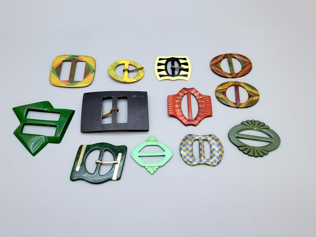 An Assortment Of 12 Art Deco Fashion Buckles: An assortment of 12 art deco fashion buckles, 1920s-40s, made of bakelite/celluloid/metal, designed in the style of the period, width: 4.5-7 cm. The green buckle was broken at the end and glued.