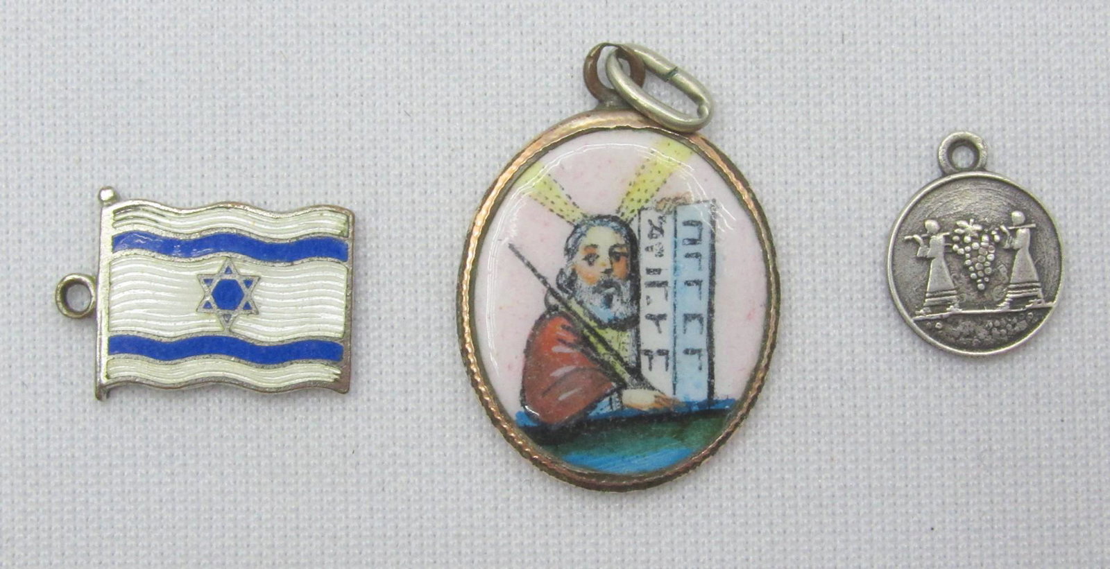 An assortment of 3 early Jewish pendants: An assortment of 3 early Jewish pendants, the first half of the 20th century, which includes: 1. A gilded oval pendant of Moses holding the tablets of the covenant decorated with colored enameling, an