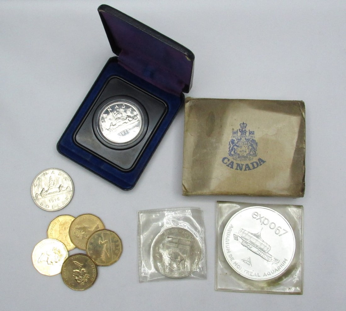 Assortment of Canadian dollar coin+ 2 tokens: Assortment of Canadian dollar coin+ 2 tokens, 1970s-1990s, 1967 Montreal Expo token and 100-year Canadian royal token for Mantua 1870-1970. One of the dollar coins is in an original packaging box. In