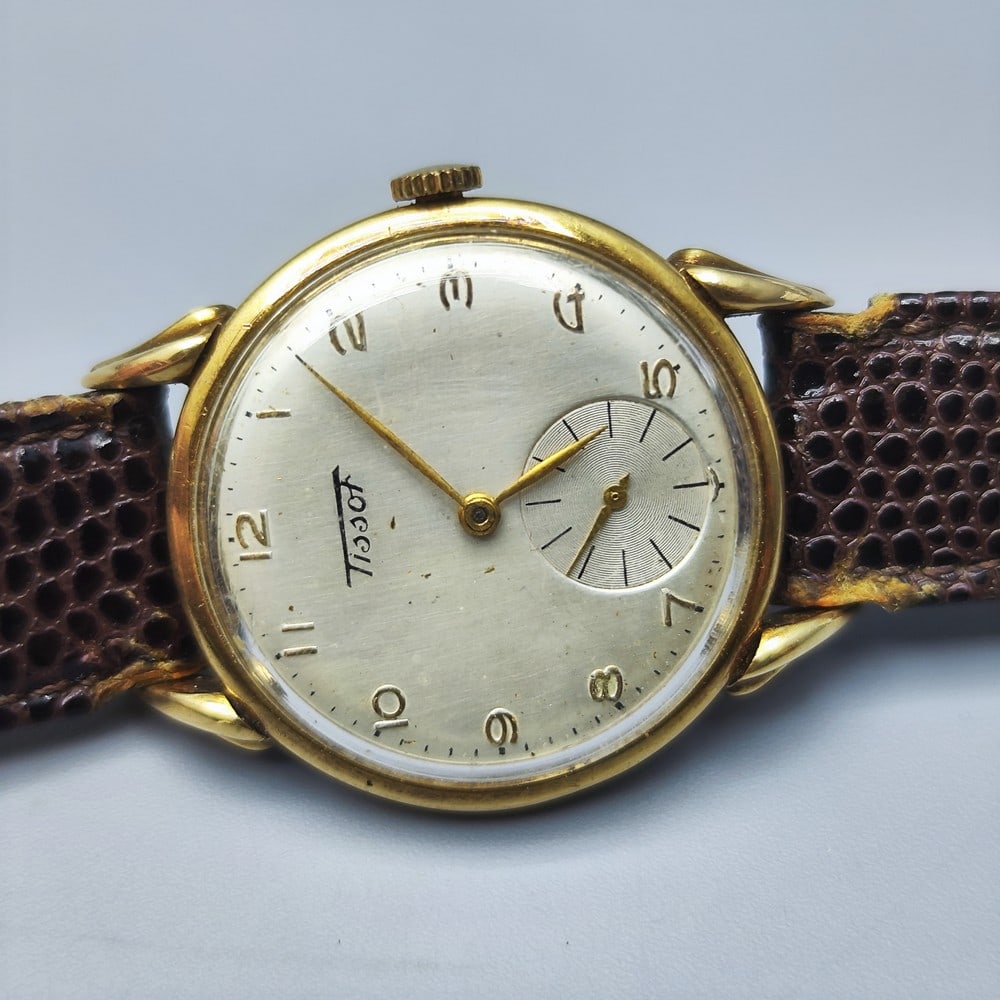 Wrist Watch Made by Tissot, Switzerland, 14K Gold Case: Wrist Watch Made by Tissot, Switzerland, 14K Gold Case, silver-plated face decorated with Arabic numerals, seperate second hand on hour 6, brown leather band (worn), mechanical (winding) movement, ful