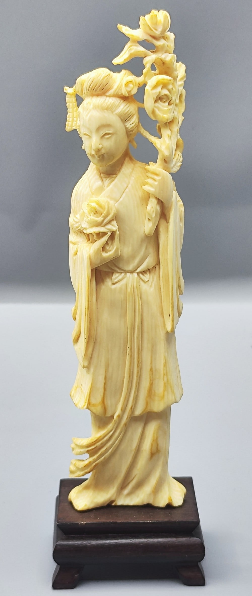 Old Chinese carved "guanyin" figurine: Old Chinese carved "Guan-yin" figurine, 20th century, carved from natural yellow organic material, the figure of a woman holding a flowering branch, attached to a matching carved wooden base, height: 