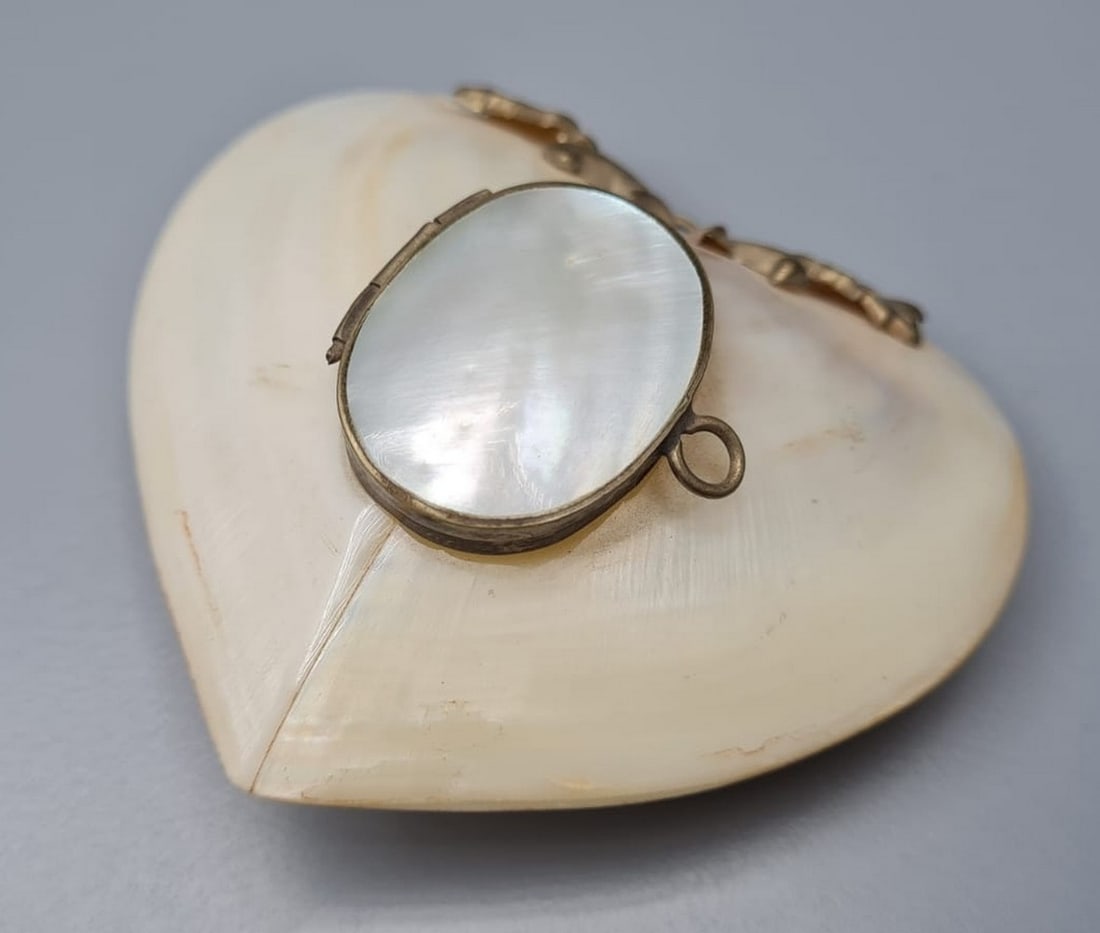 Old mother-of-pearl "heart" pill box: Old mother-of-pearl "heart" bullet box, 20th century, oval opening lid combined with silver metal plating on the front, with a holding loop on the top, dimensions: 6X6.5 cm, 22 g. Hairline crack on th