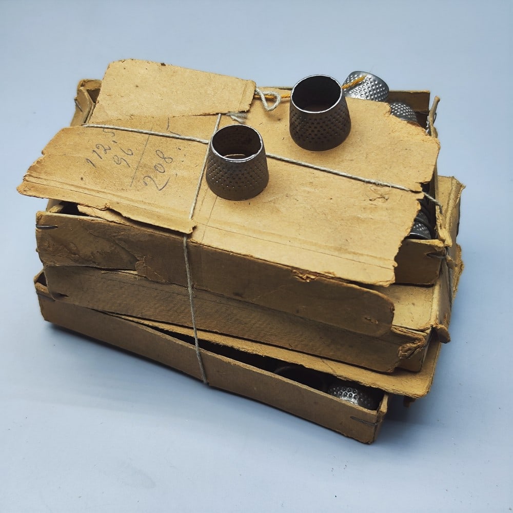 A large assortment of identical metal thimbles in original boxes.: A large assortment of identical metal thimbles in original boxes, circa mid-20th century, never used, in the original cardboard boxes, not individually counted: probably a few hundred, with a total we