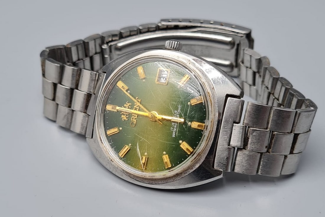 Vintage wristwatch made by Orient: Vintage wristwatch made by Orient, Japan, circa 1960s, Water Resistant 17 Jewels, mechanical movement (winding), original stainless steel case and band, green metallic face, gold-lined numerals, date 